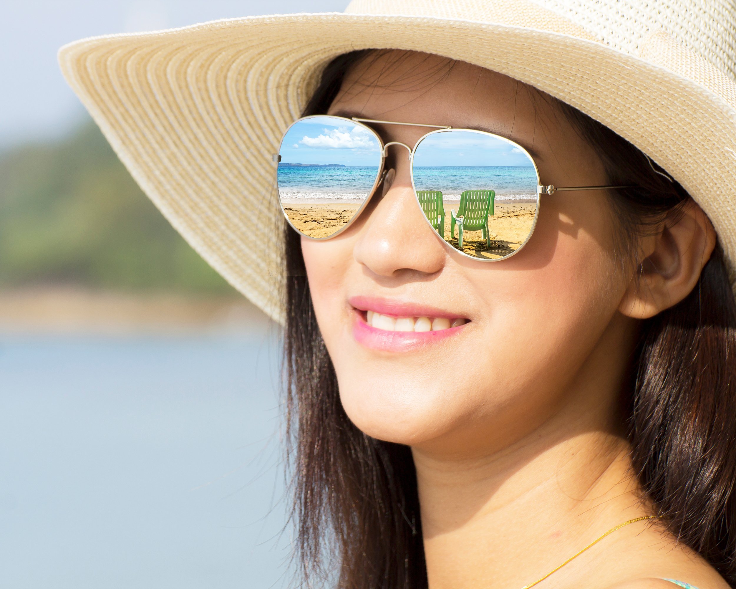 Smiling beautiful woman on a beach wearing a hat and sunglasses