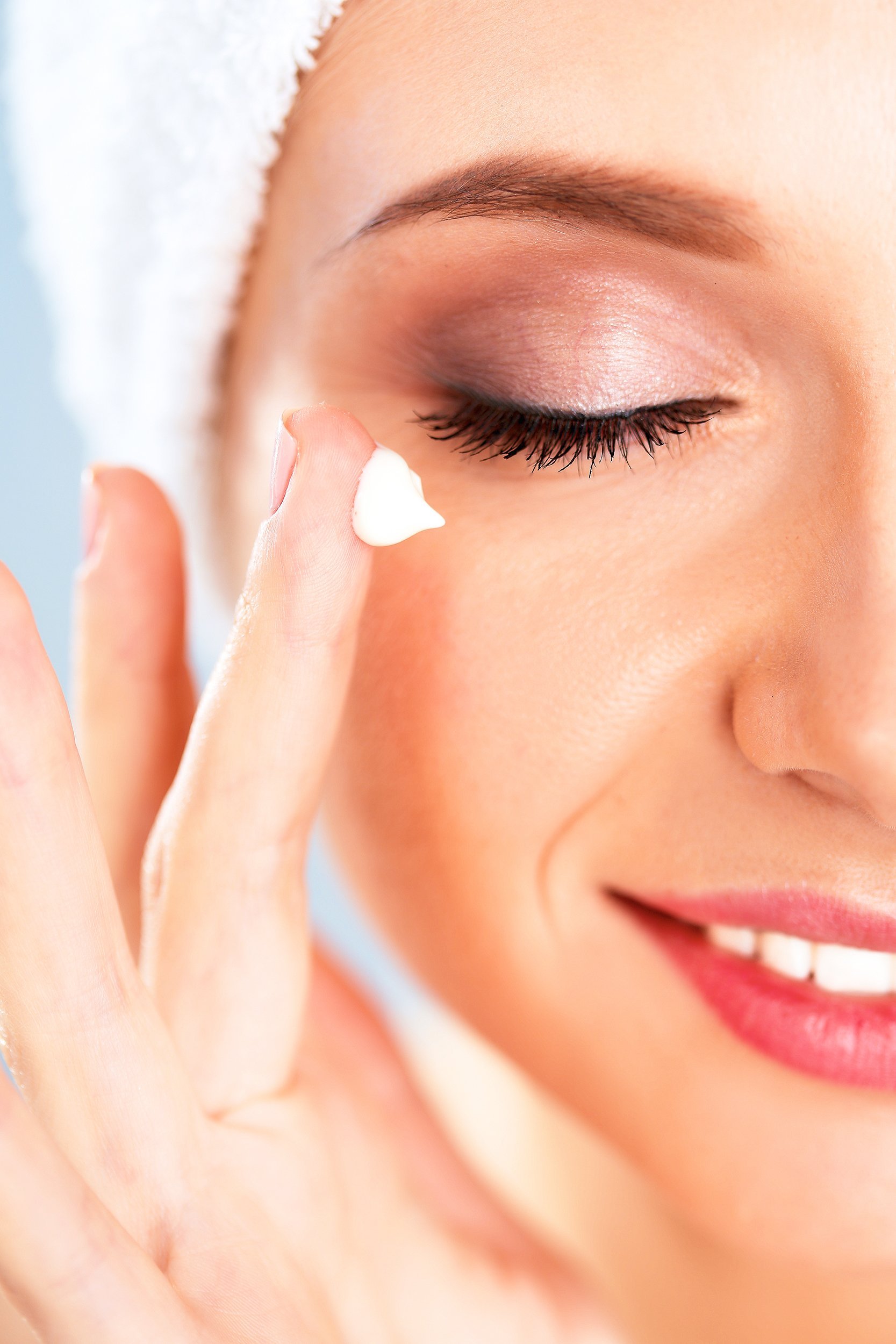 young woman applying a creme on her face with ring finger