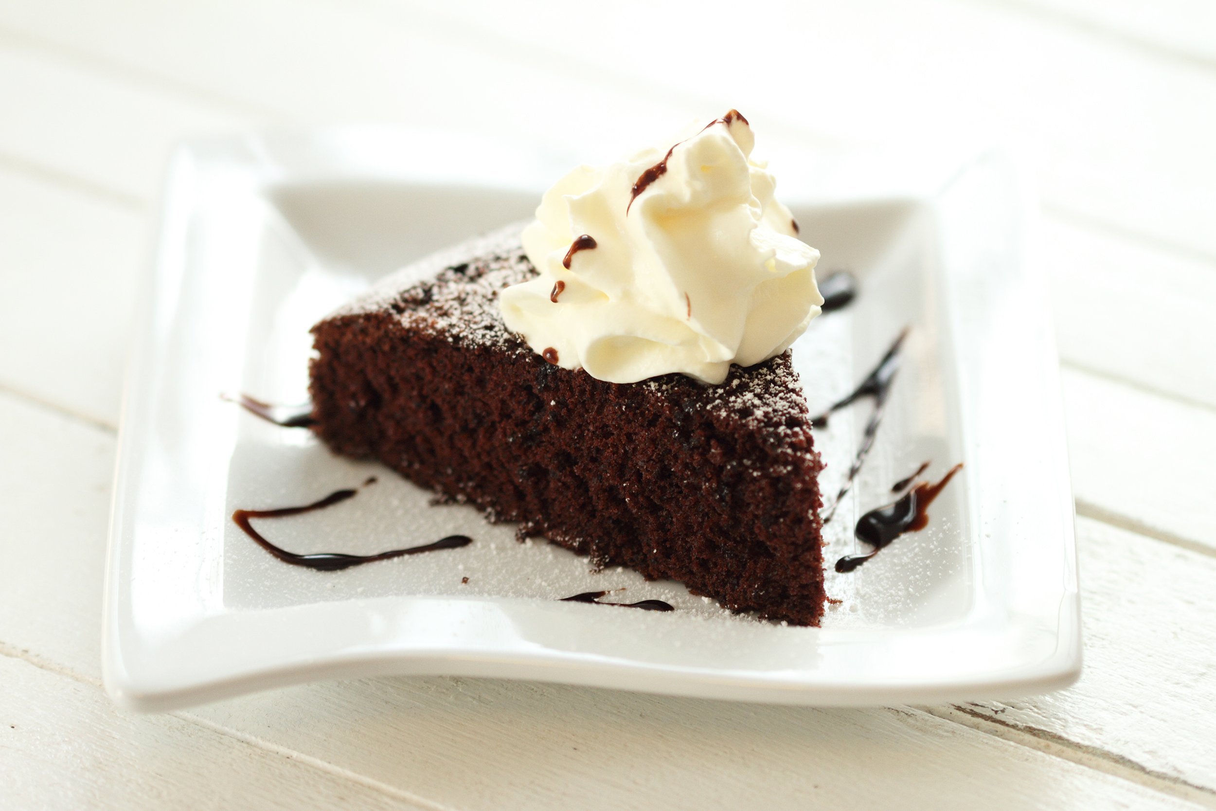 chocolate cake on white plate with whipping cream