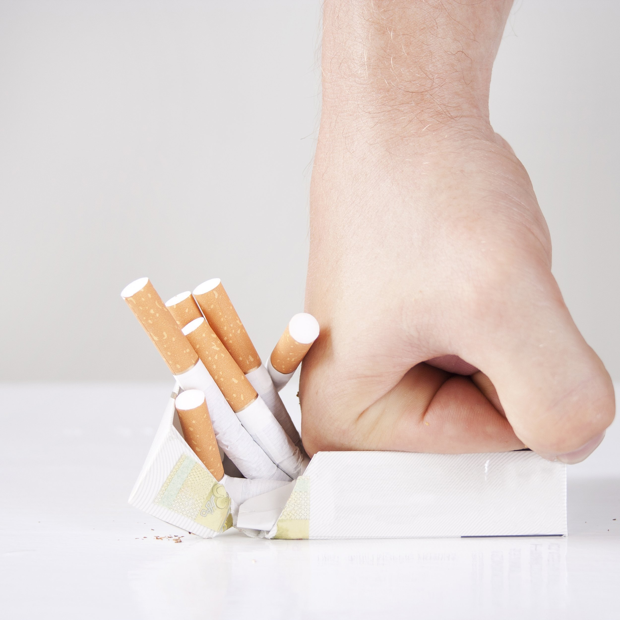 man's hand crushing cigarettes