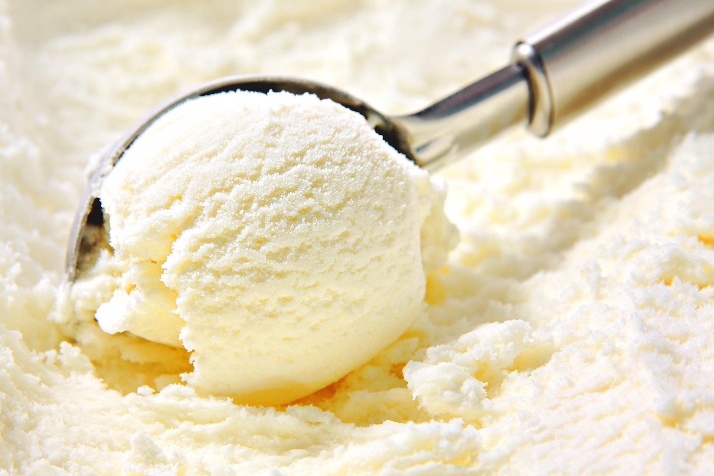 vanilla ice cream being scooped out of a container with a utensil