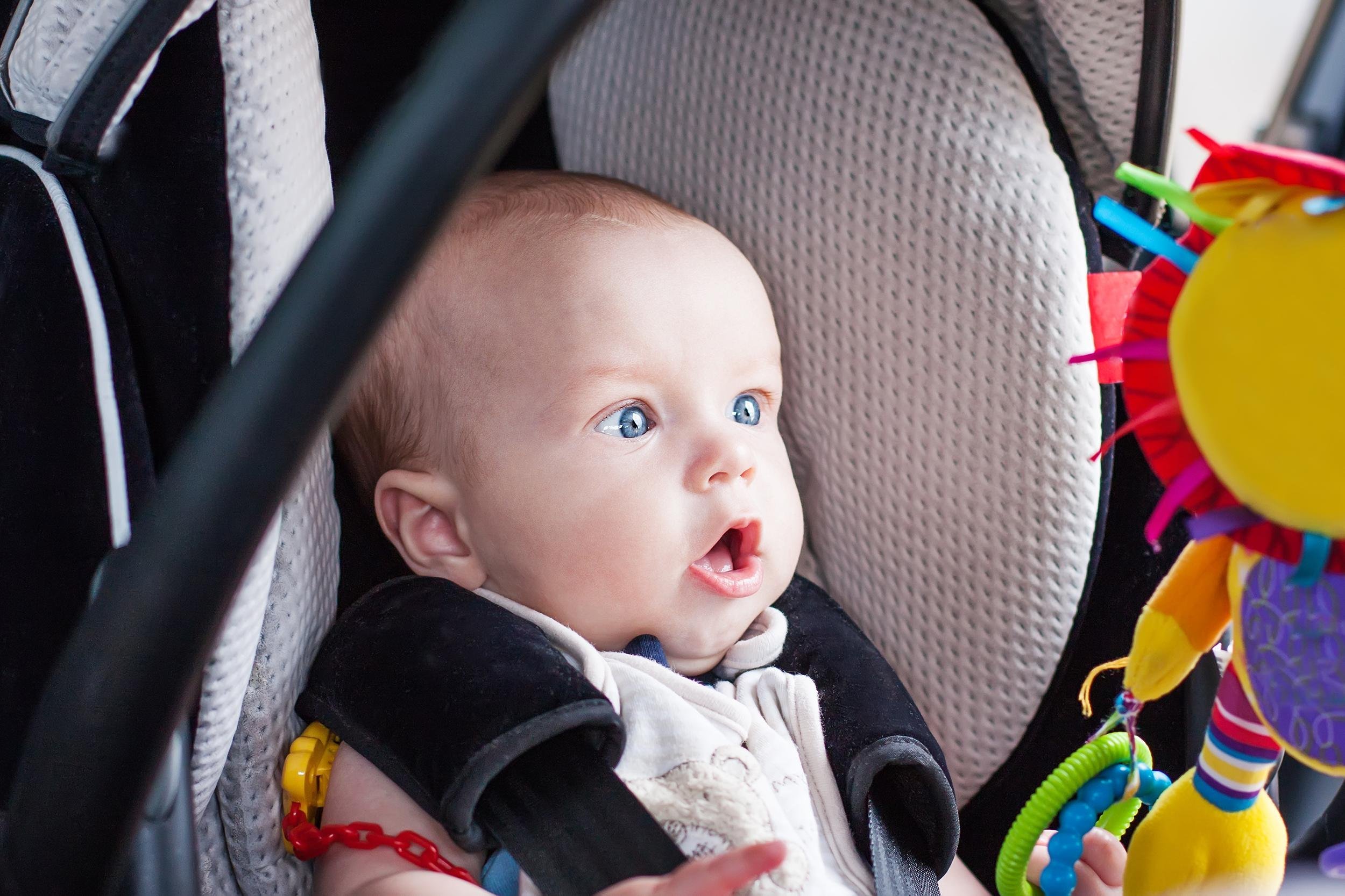 baby boy in car seat stares at the toy