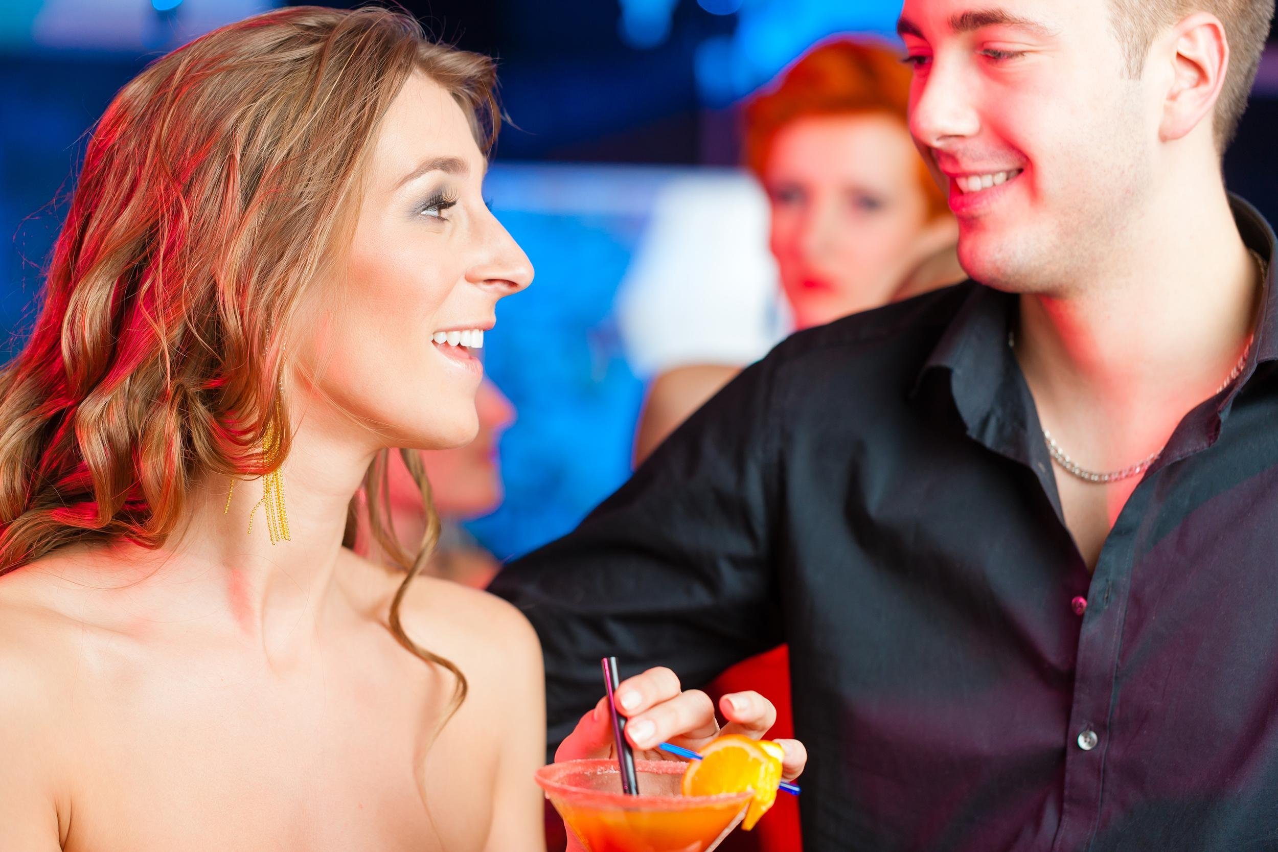 young couple in bar or club drinking cocktails