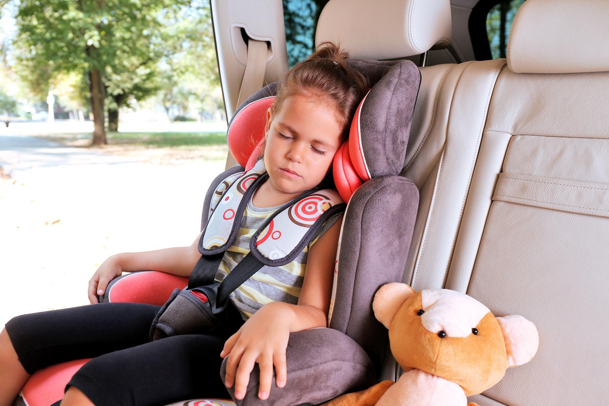 child sleeping in back of car in car seat