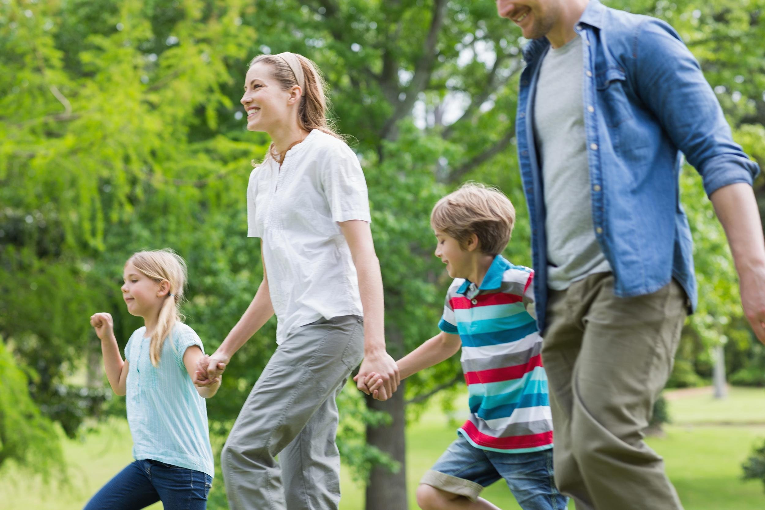 side view of parents and kids walking in the park