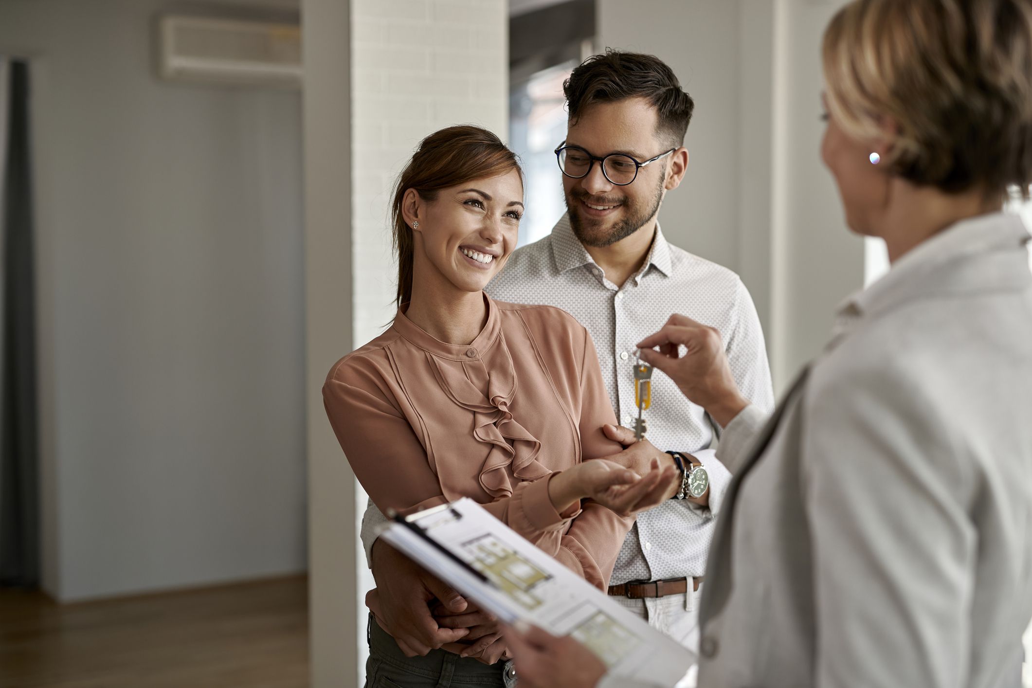 young happy couple receiving keys of their new home from real estate agent