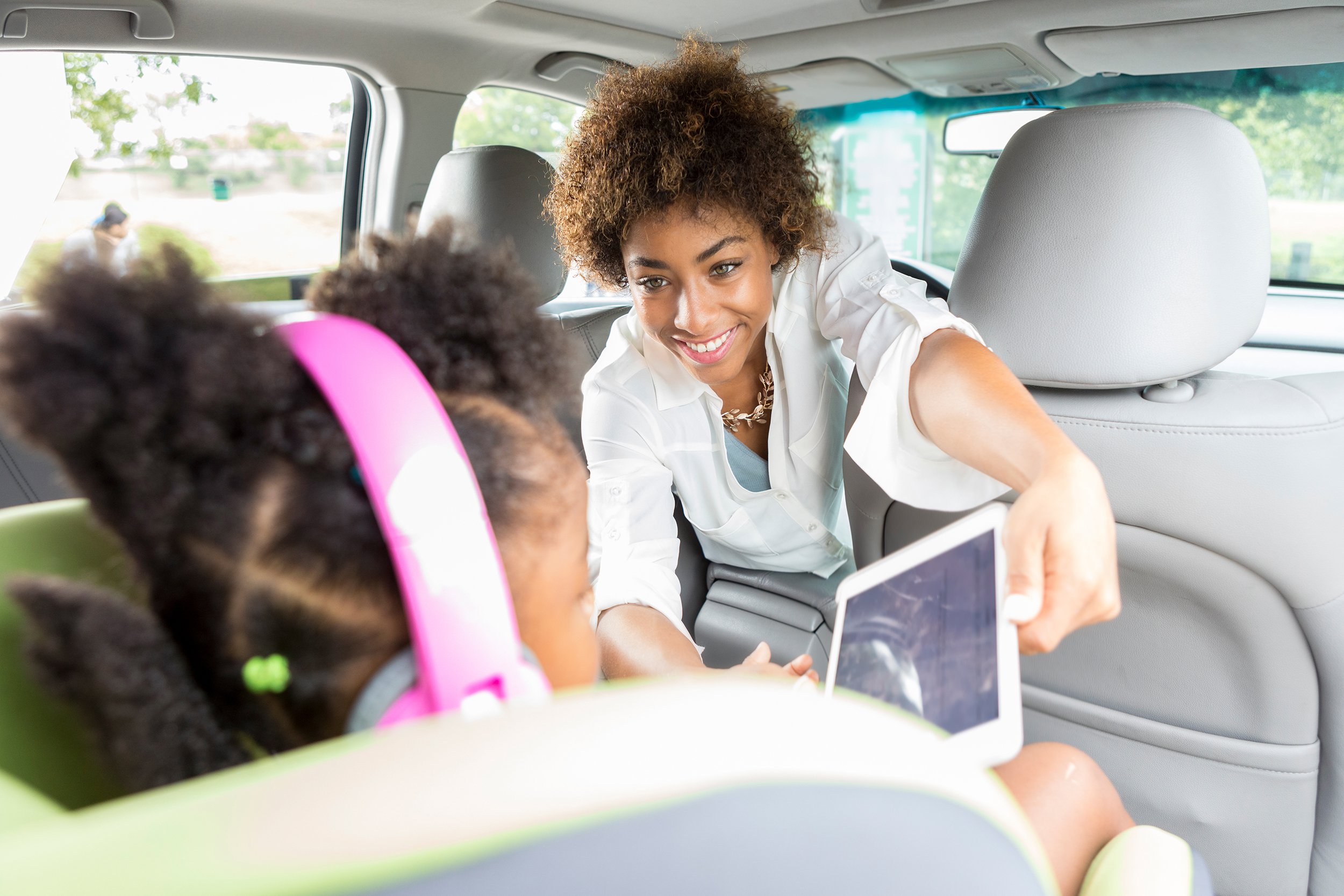 young mother gives daughter electronics before car trip
