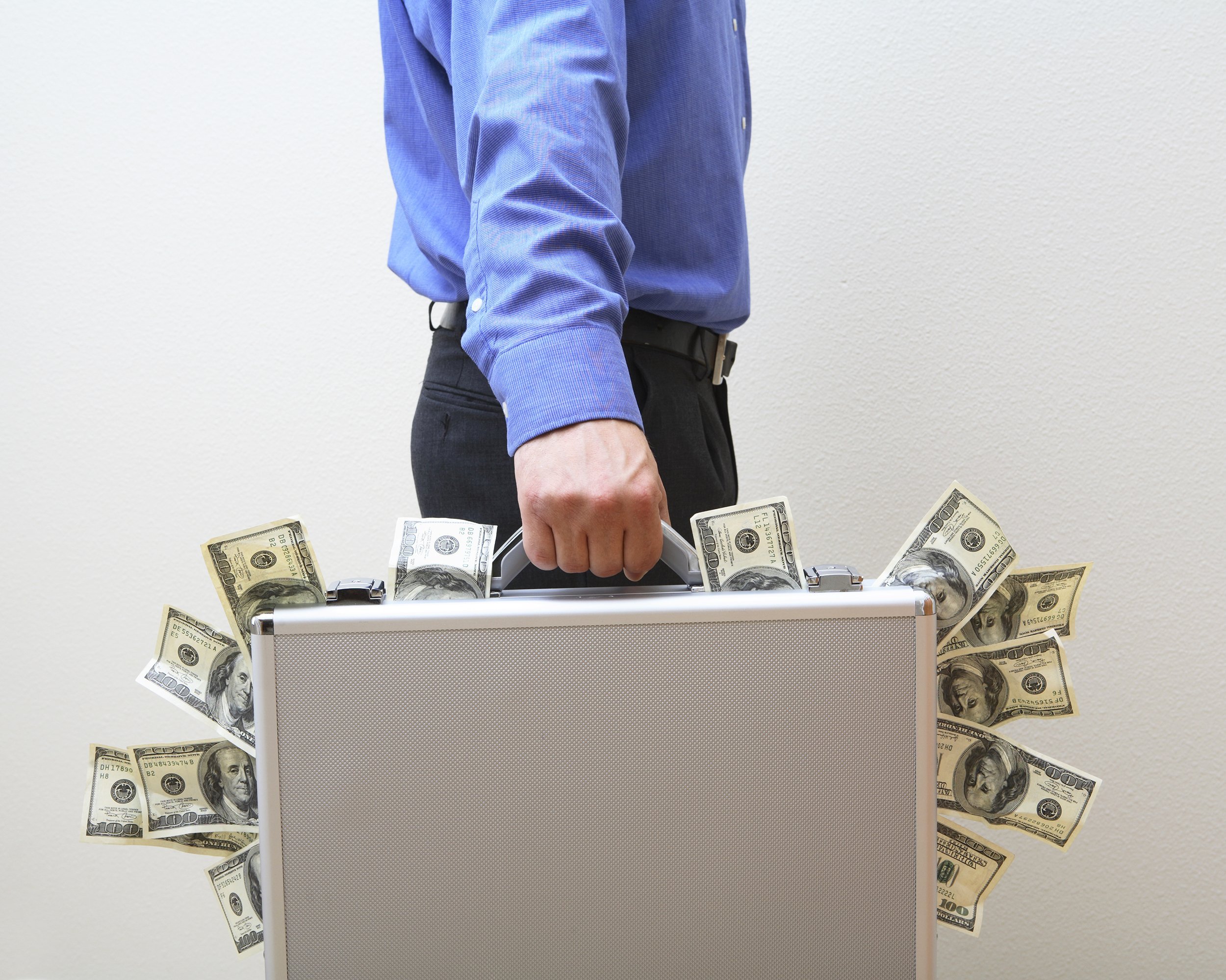 businessman carrying briefcase overflowing with money