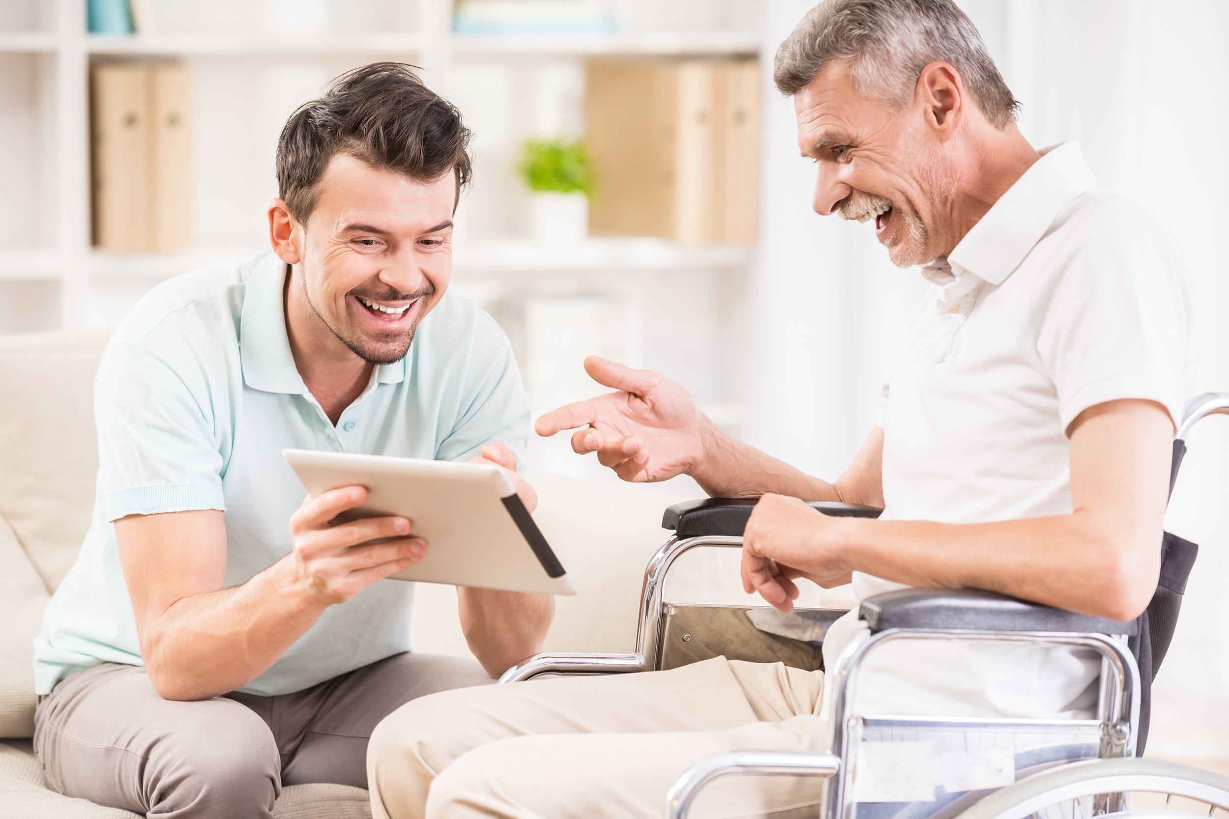smiling handsome man taking care about his elderly father in wheelchair