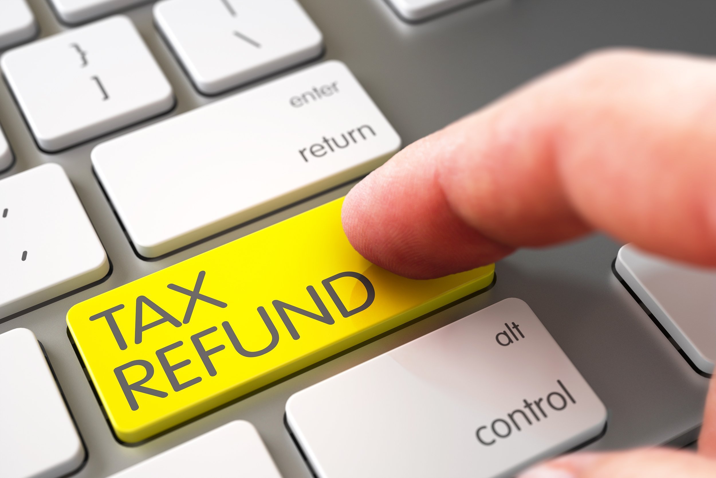 hand using laptop keyboard with tax refund yellow button