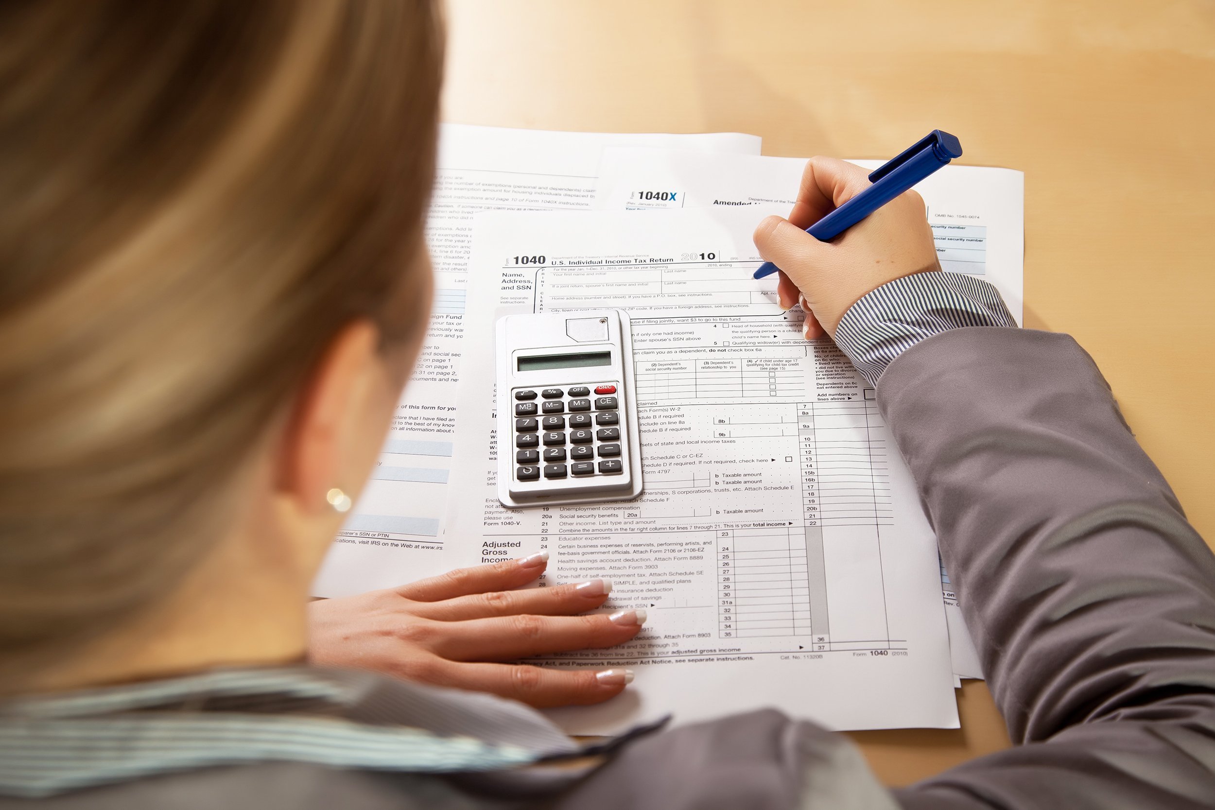woman hand filling income tax forms with calculator