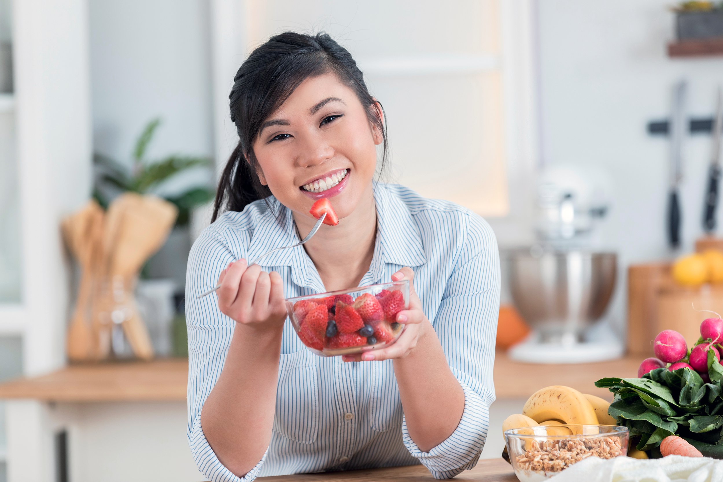 Happy woman eating a bowl of strawberries