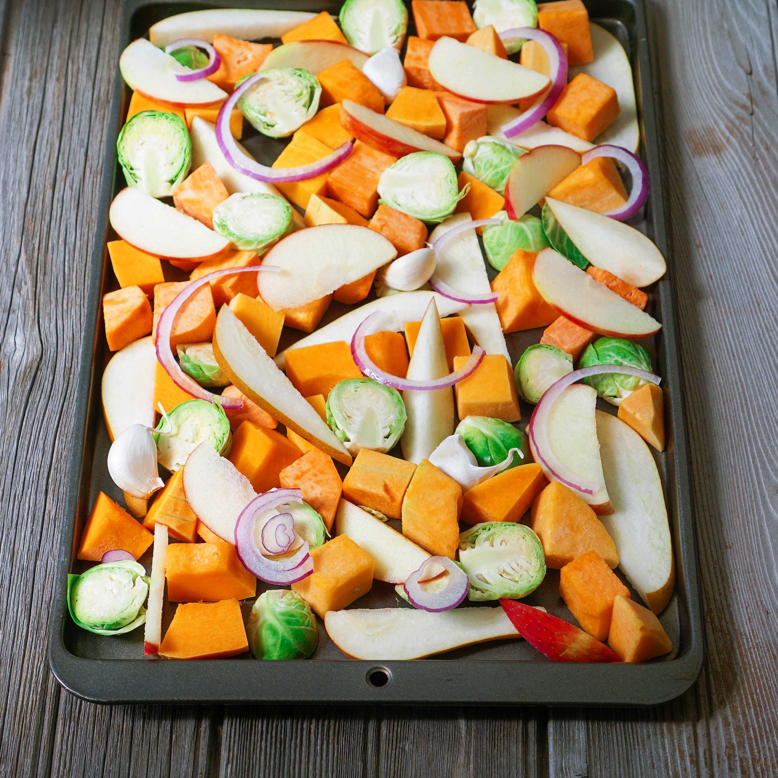 Sheet pan of assorted vegetables prepared for roasting