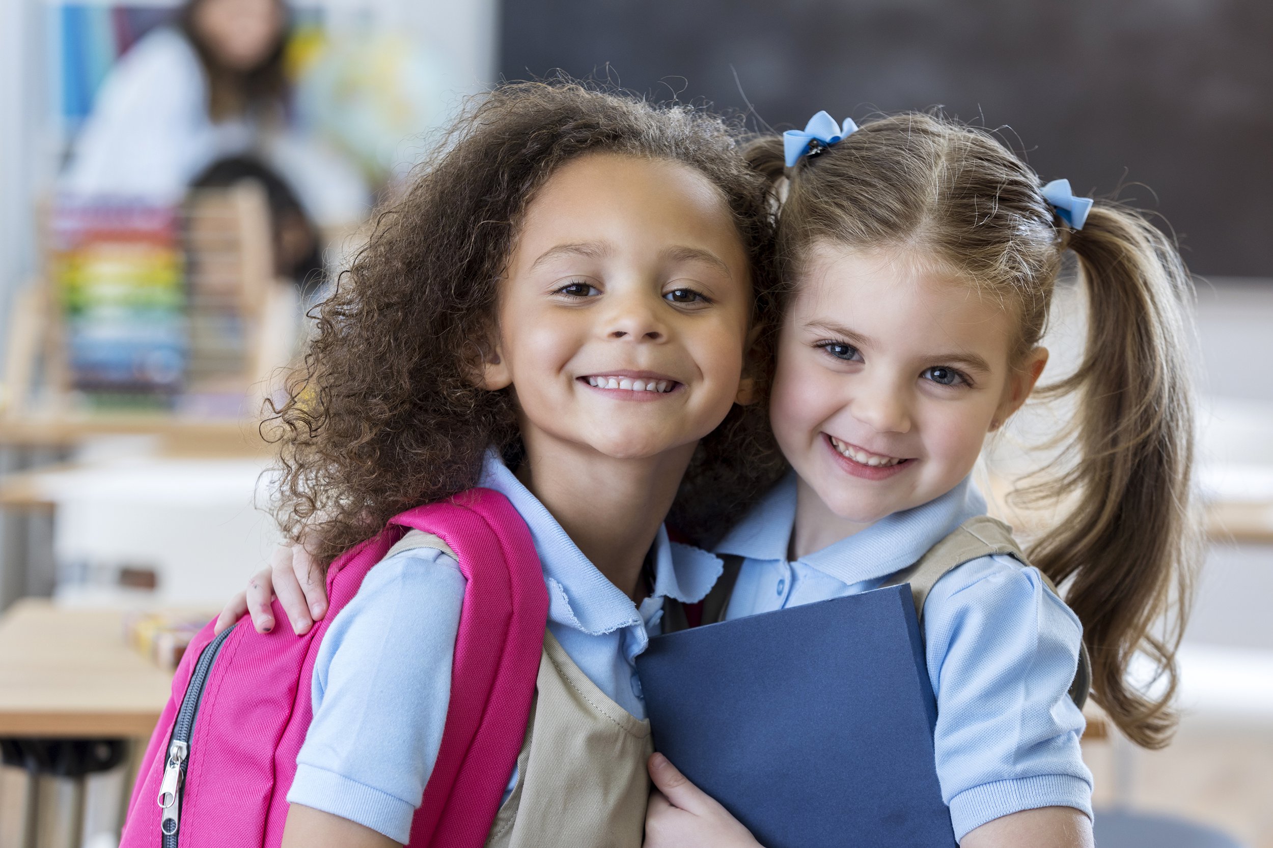 Two private elementary school girls wearing uniforms and hugging each other