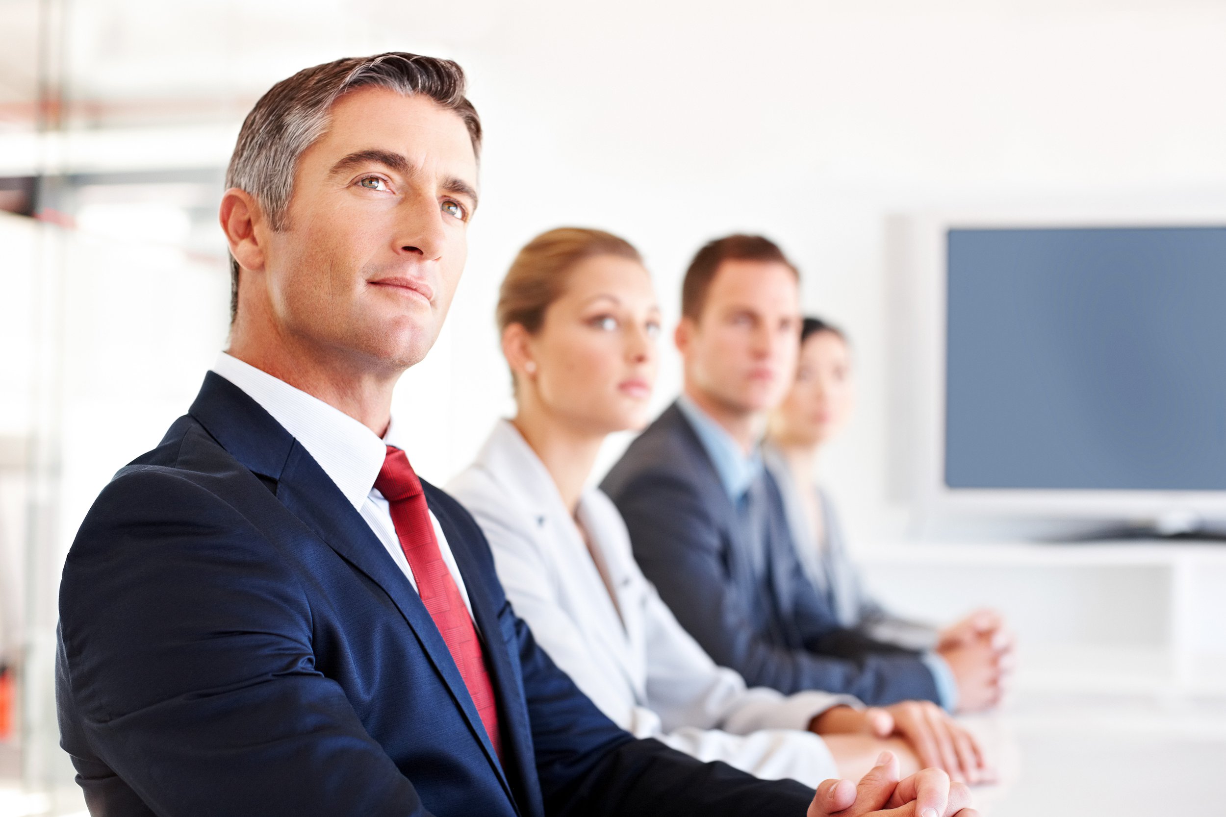 Businessman sitting at a conference table in an office looking at someone