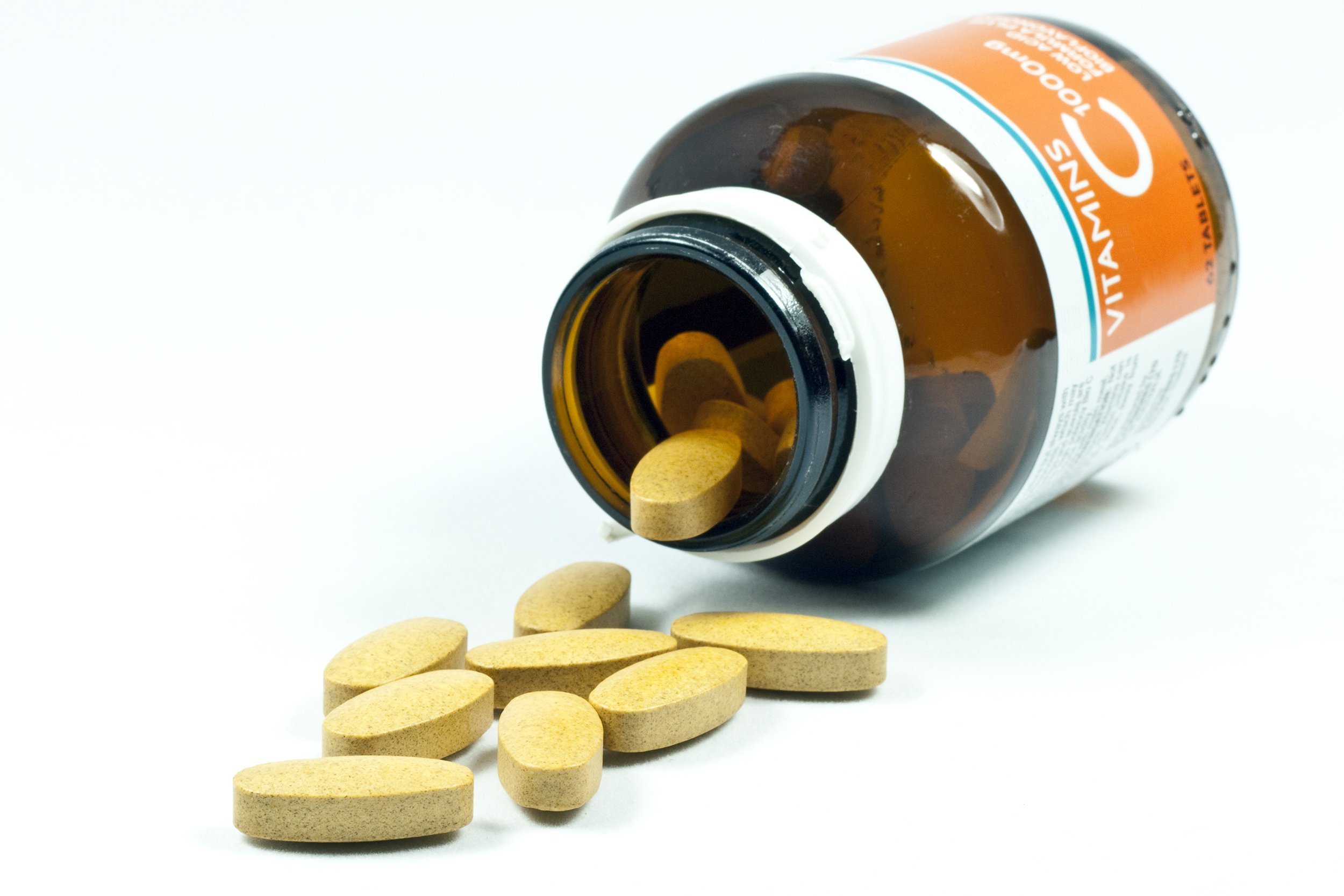 vitamin C tablets spilling out of bottle
