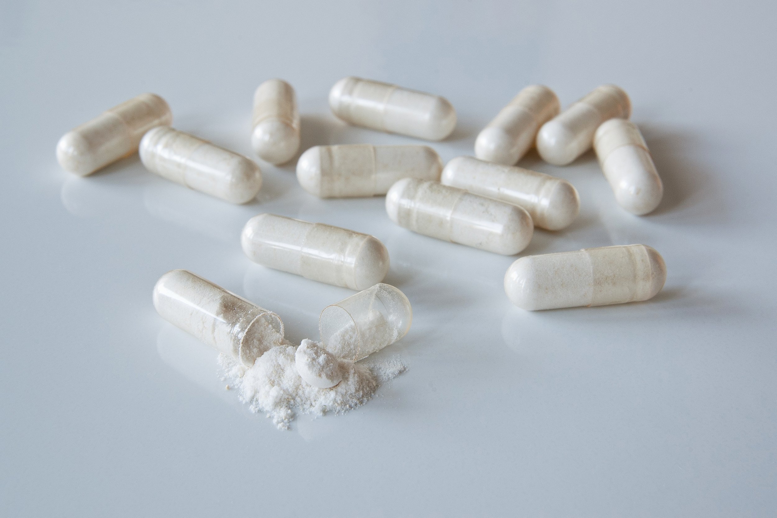 white medicine capsules probiotic powder inside, one capsule open