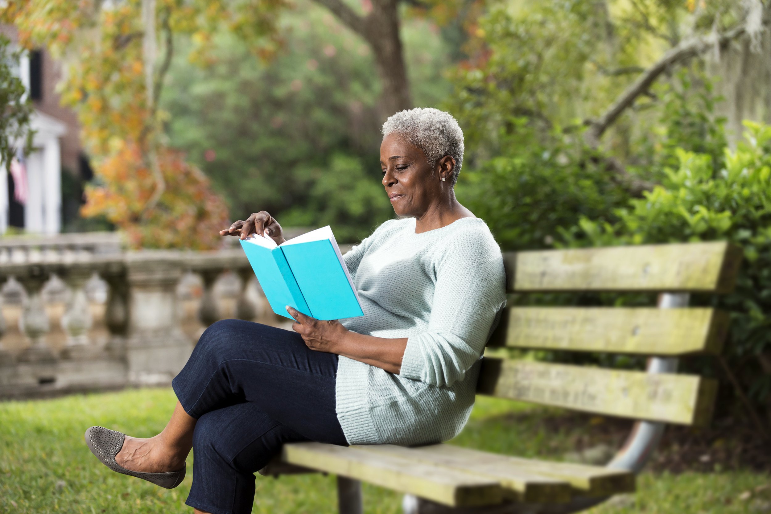 Senior woman reading a book on a park bench