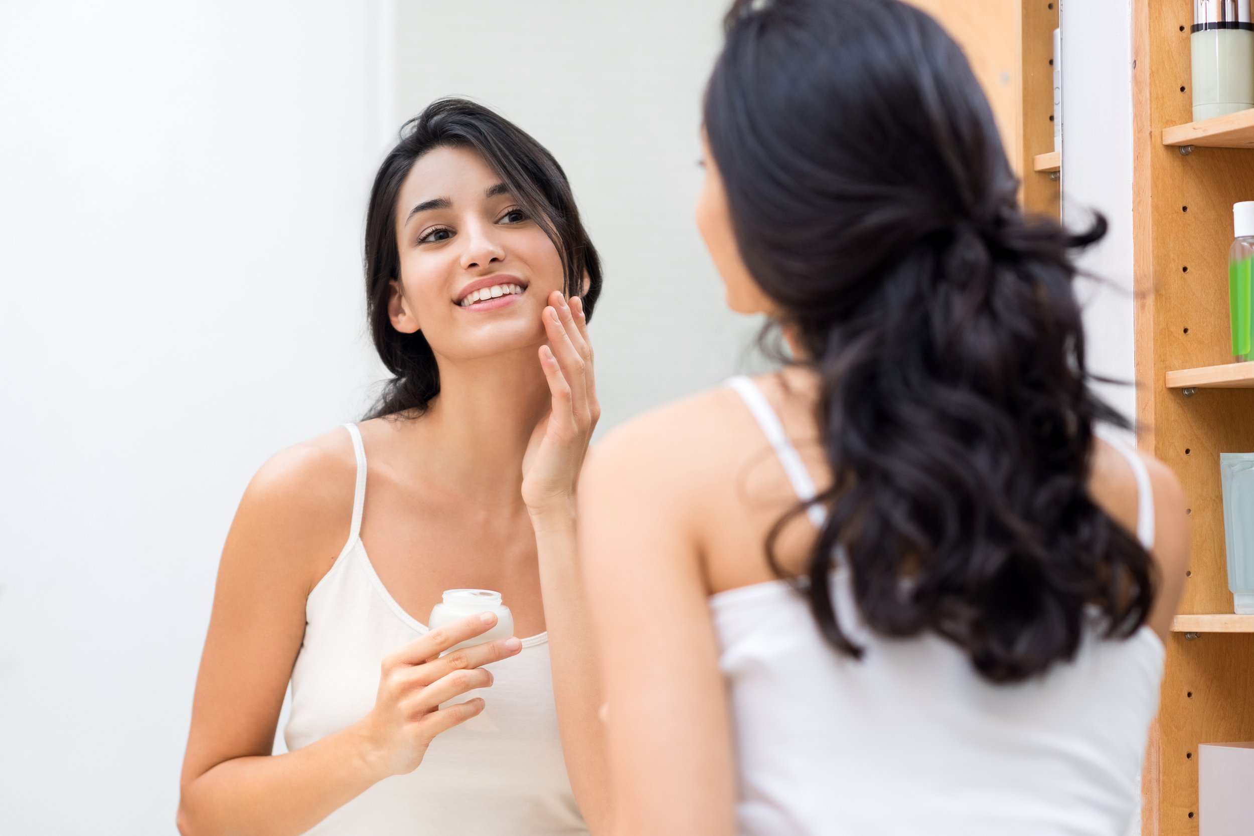Woman applying moisturizer to her face