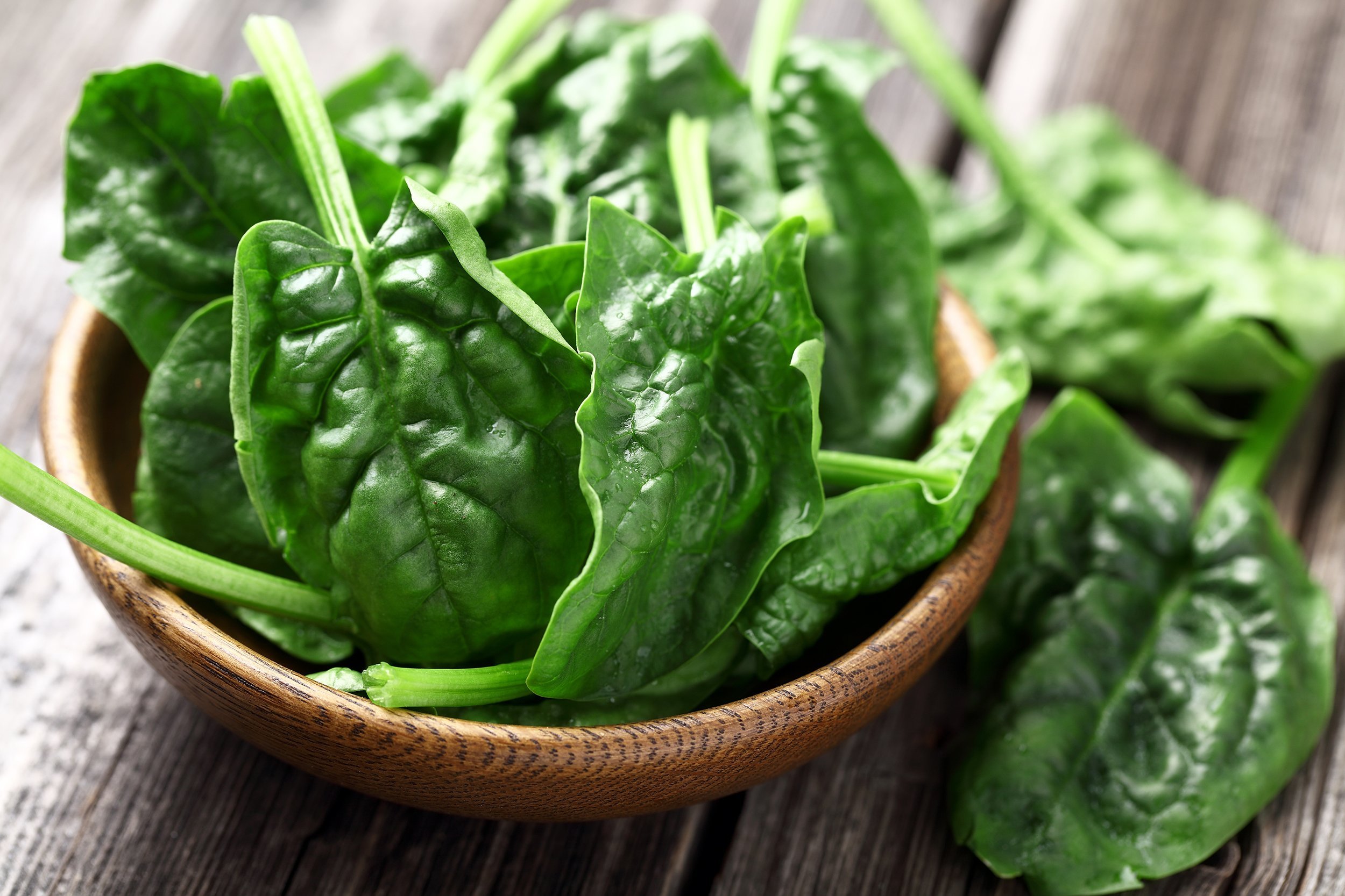 spinach leaves in wooden bowl on wooden table