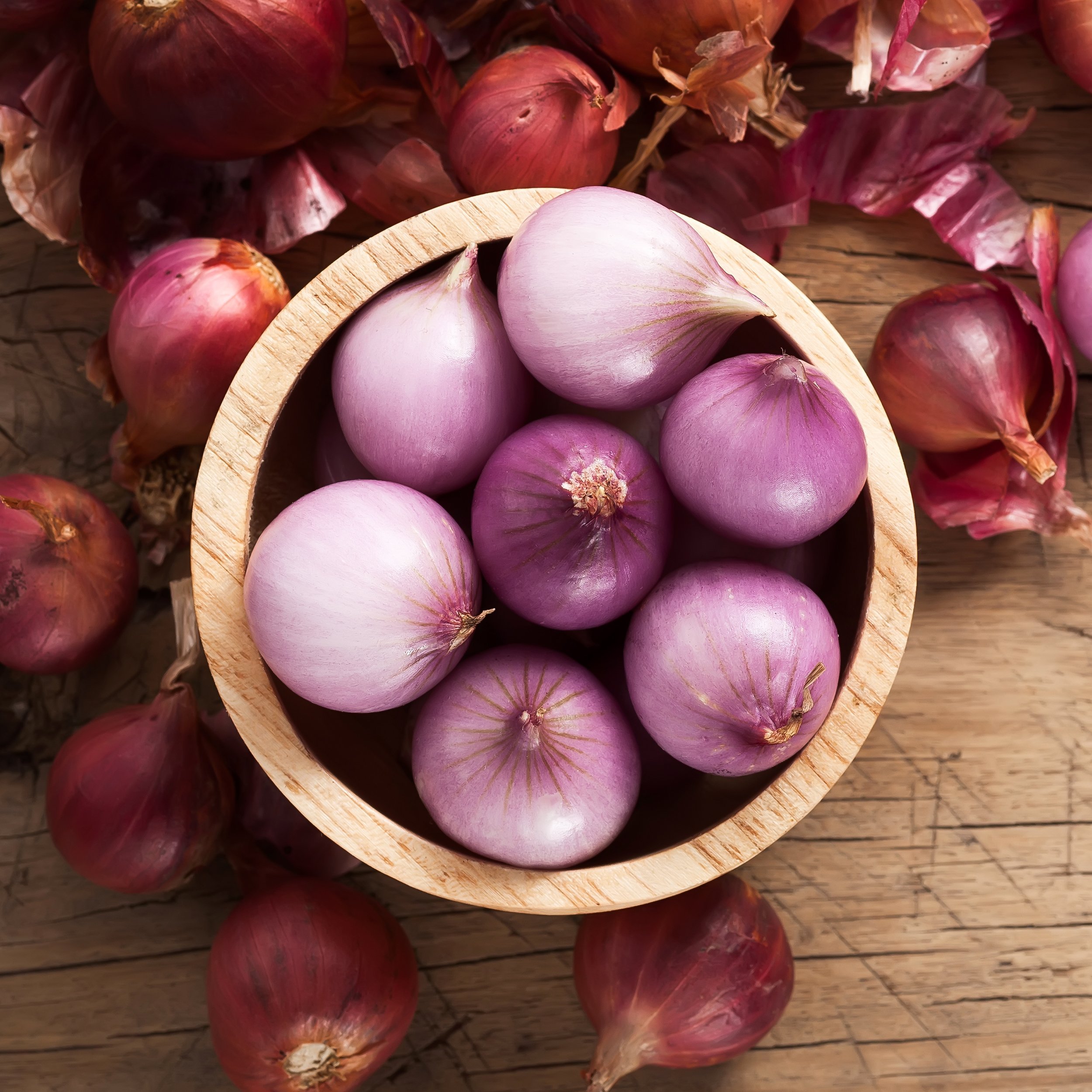 shallots in wood bowl on wooden table