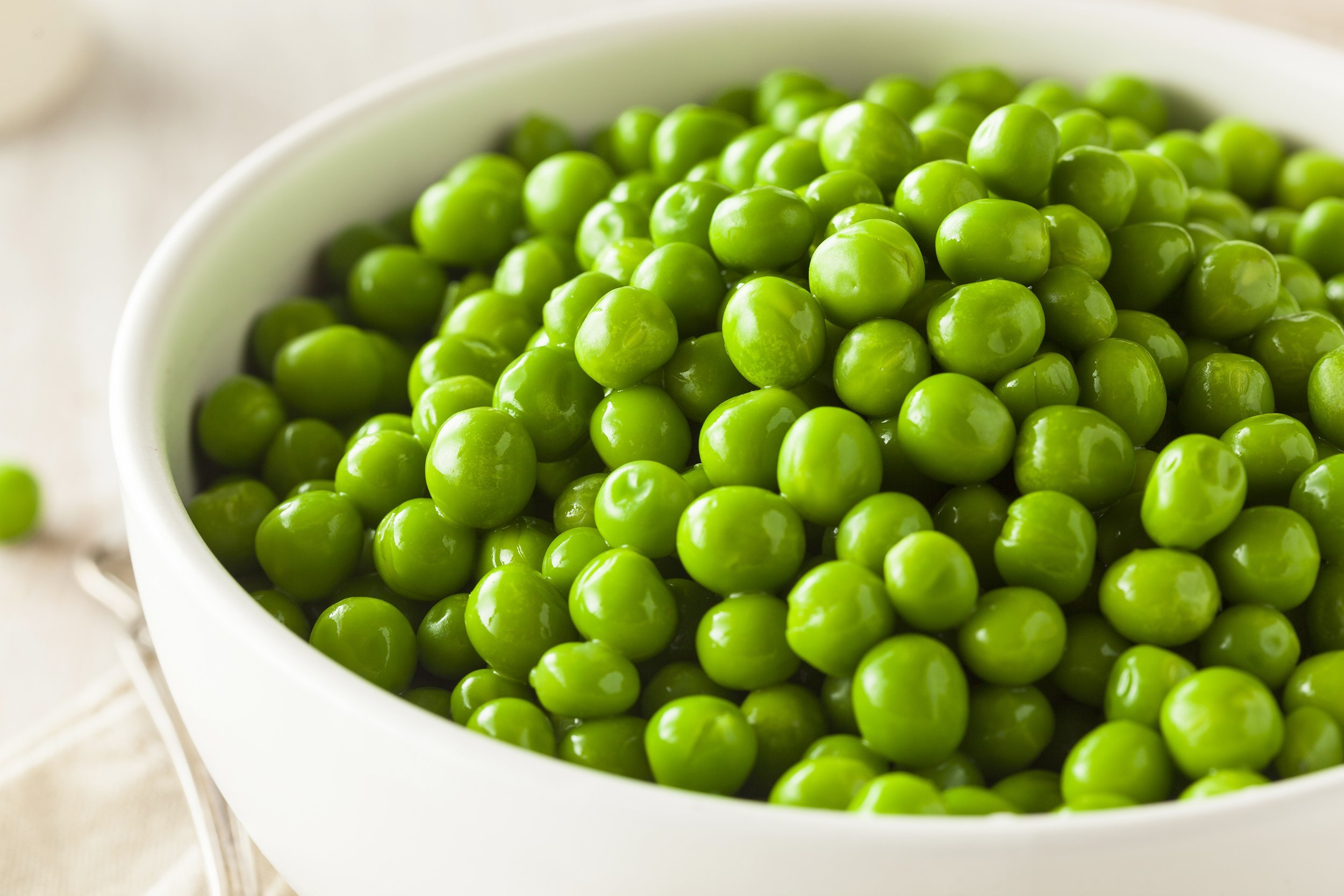 steamed fresh green peas in a white bowl