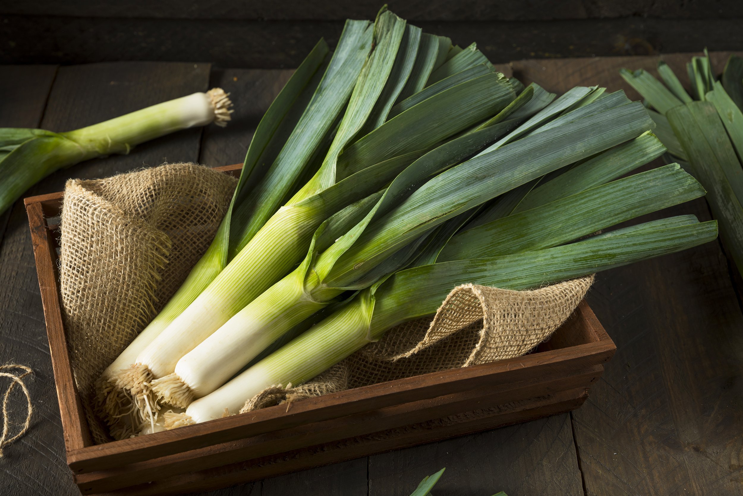 leeks in wooden container on wood table
