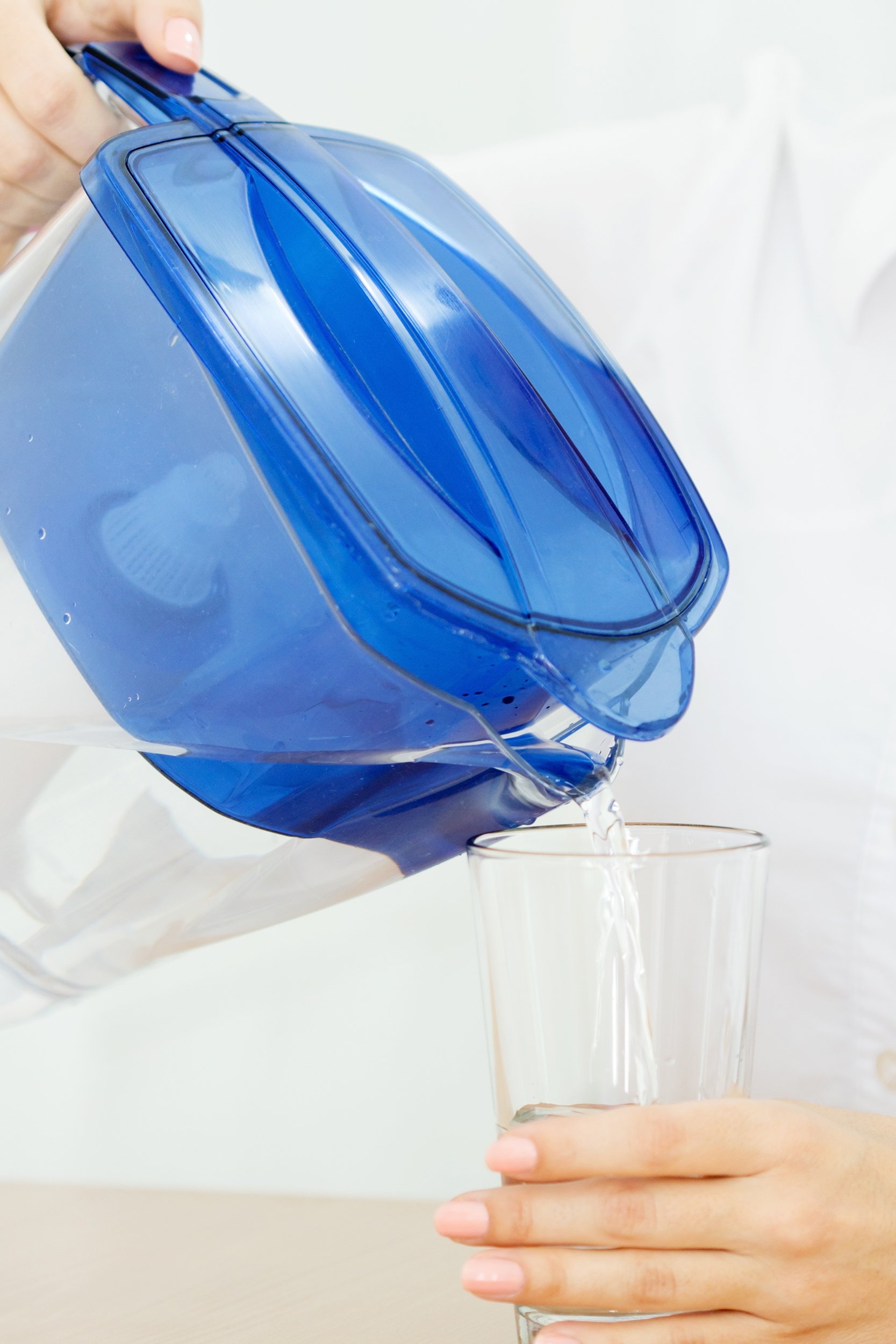 pouring water from water purifier pitcher into glass