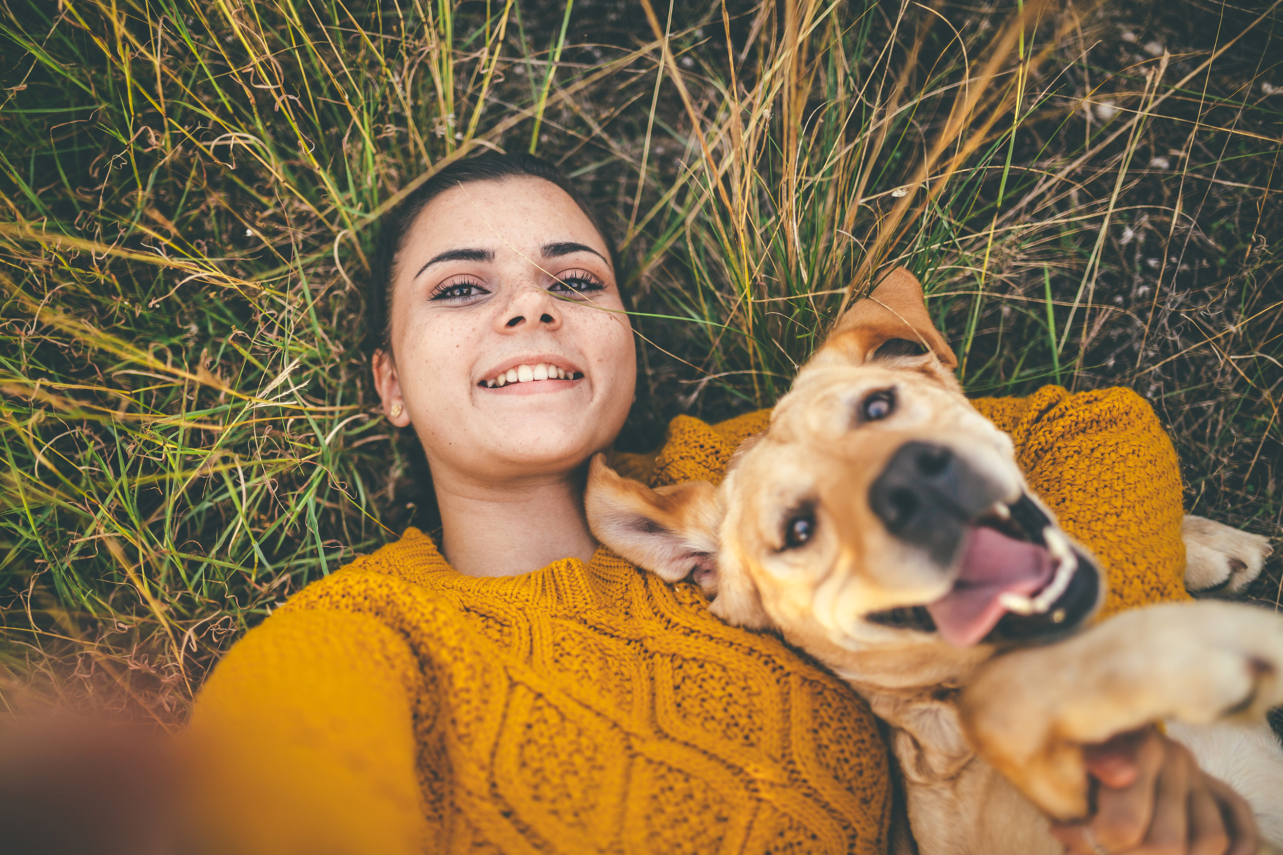 Woman taking a selfie with her dog in the grass using a filter