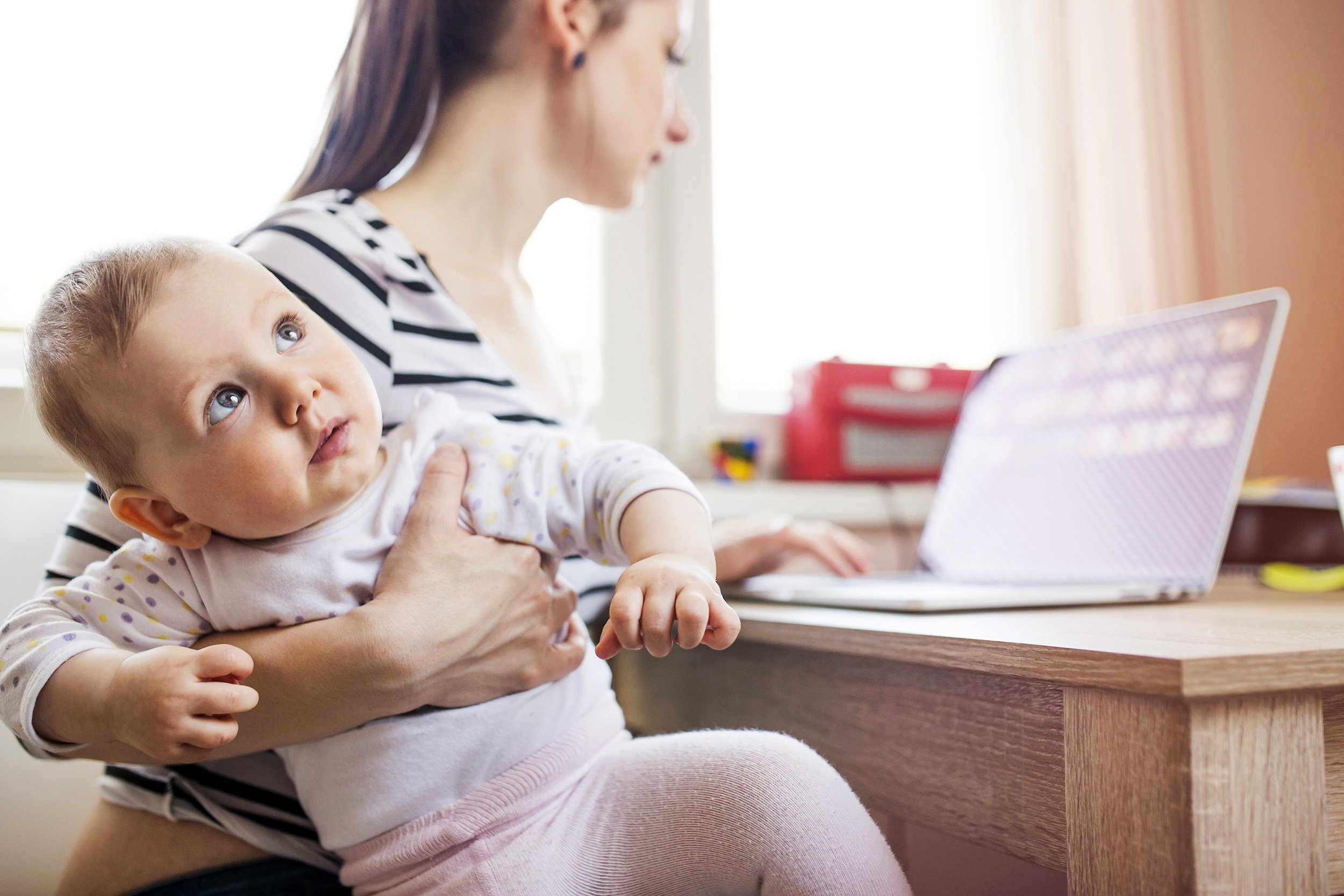 Young mother in home office with computer and her daugher