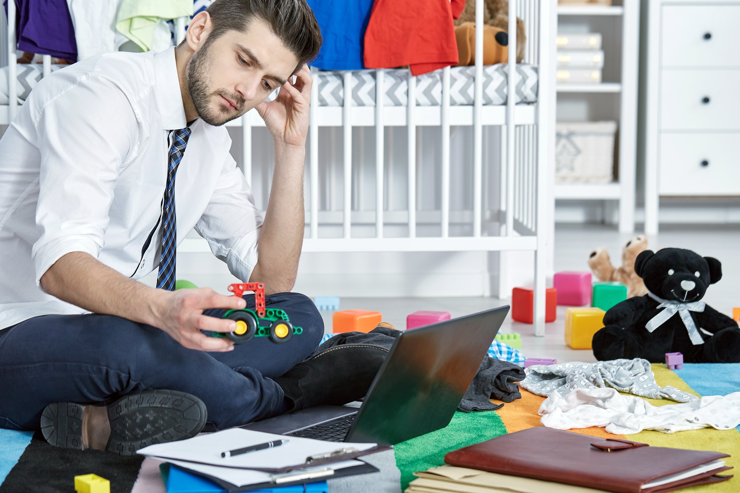 Single father sitting in messy room and trying to work