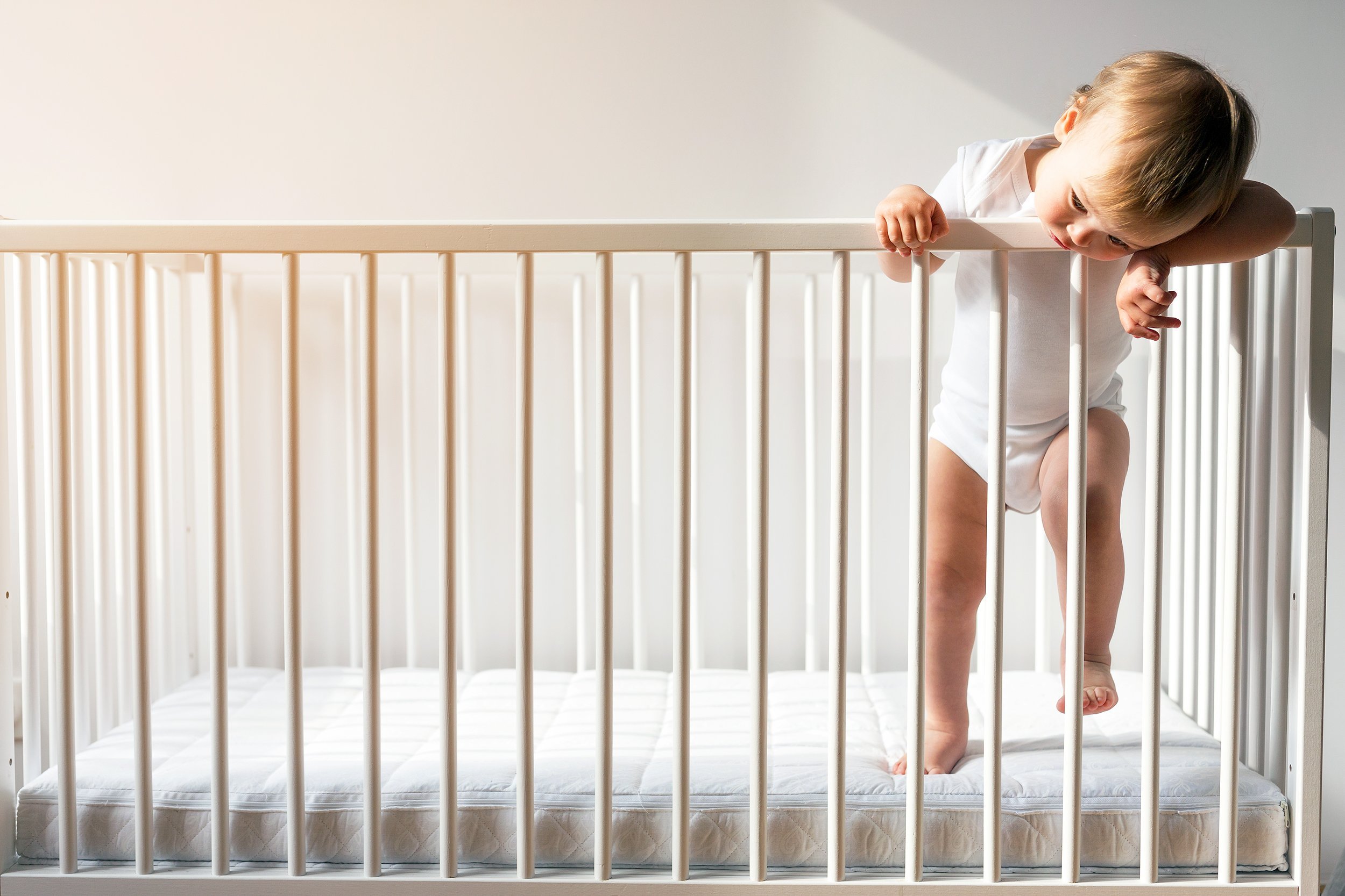 lonely baby standing alone in crib