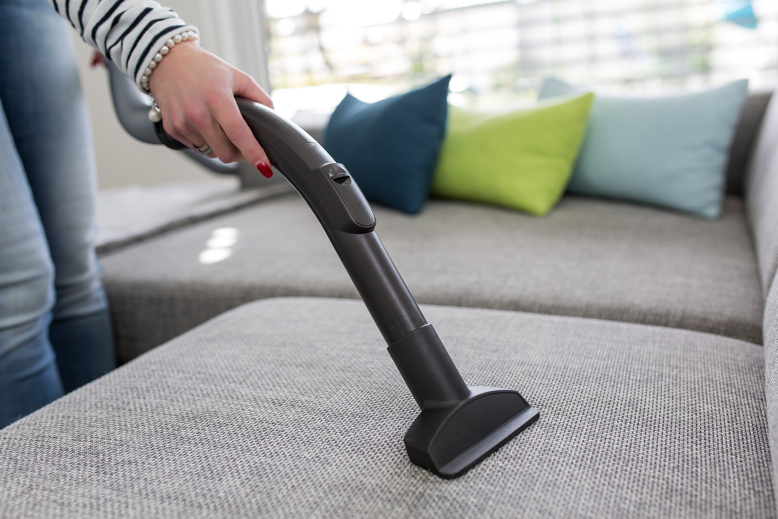 Cleaning the sofa with a vacuum cleaner