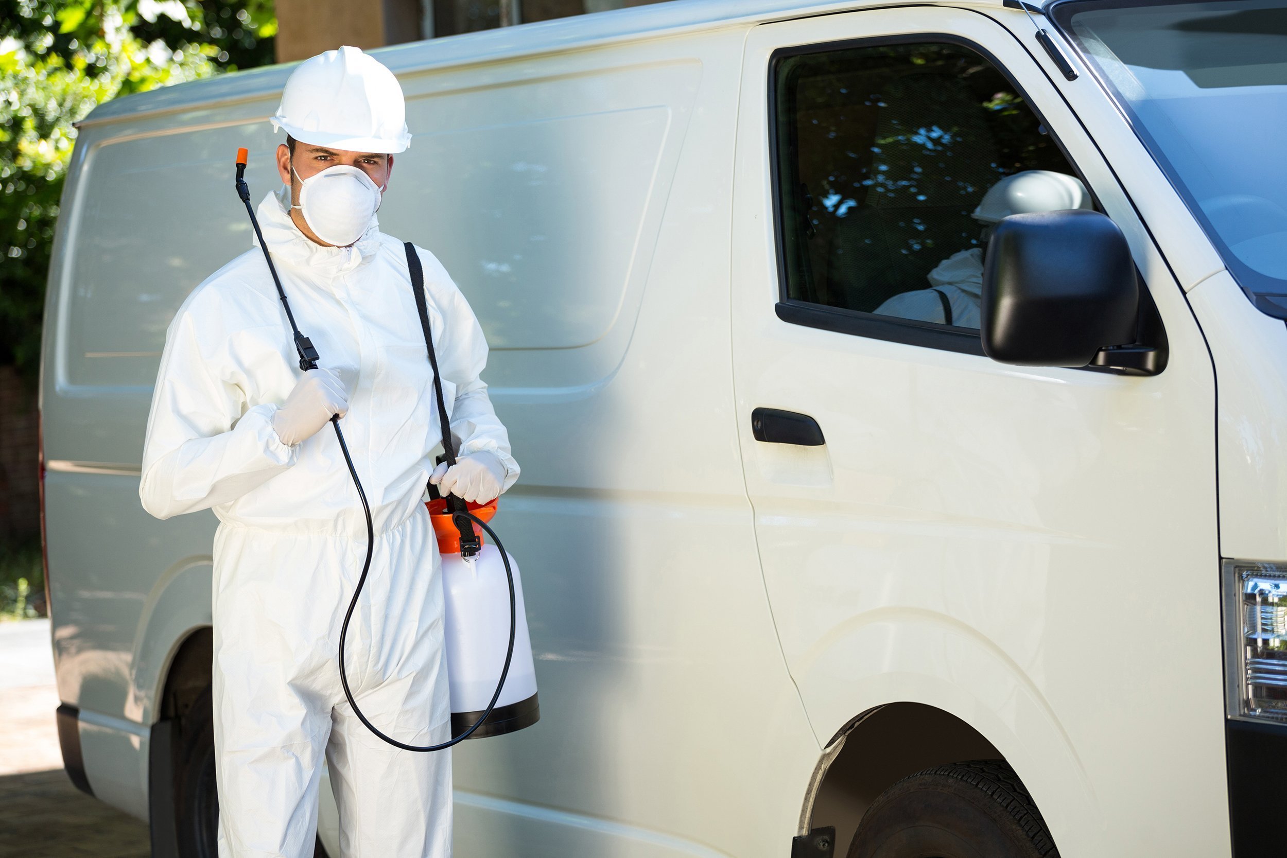 Pest control man standing next to his white van