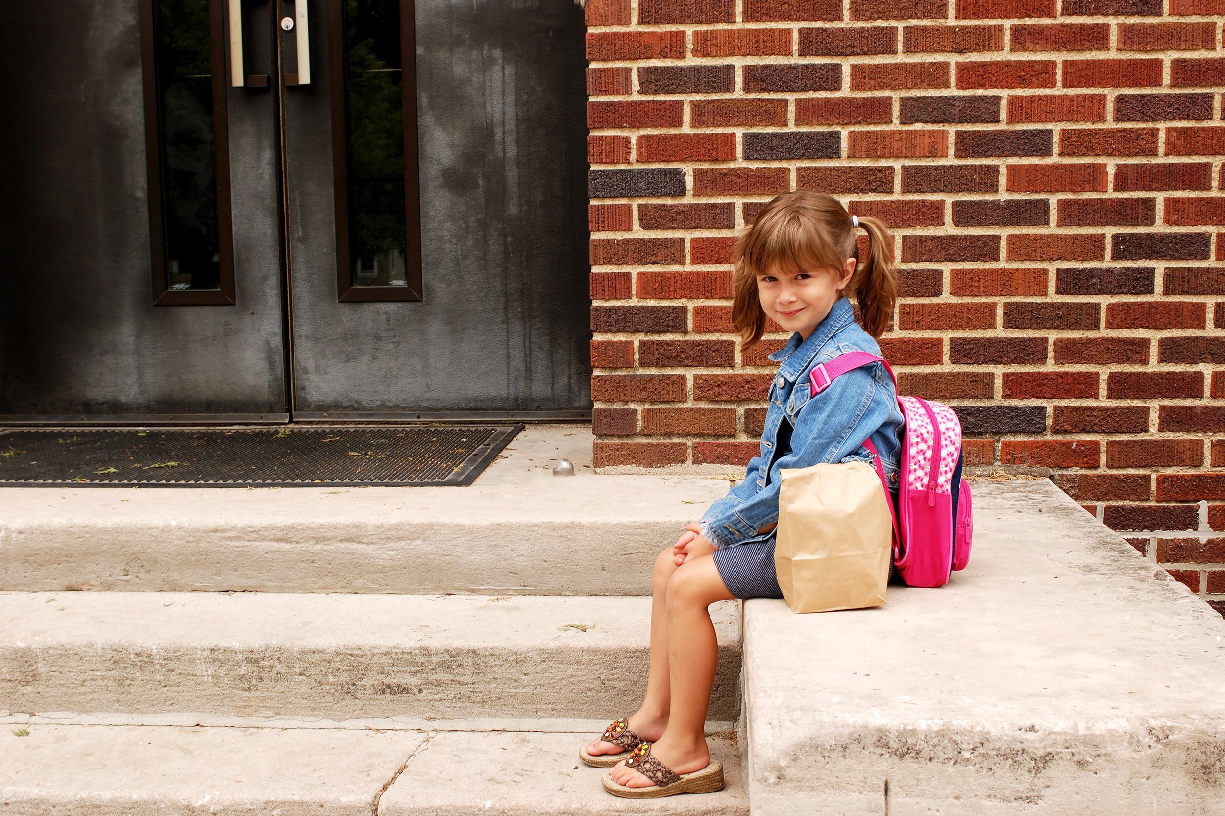 Little girl sitting alone outside of school