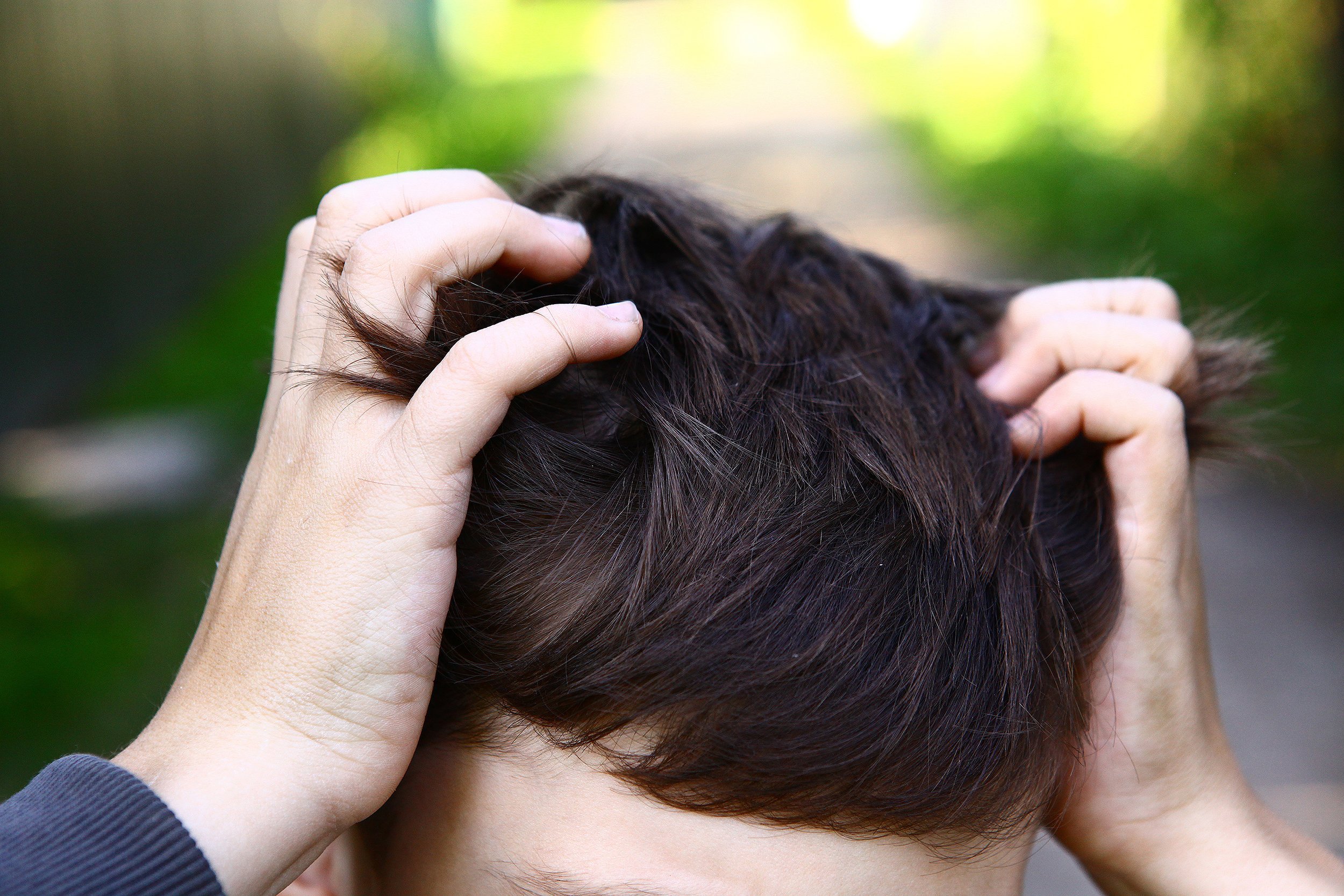 Close-up of boy scratching the top of his head