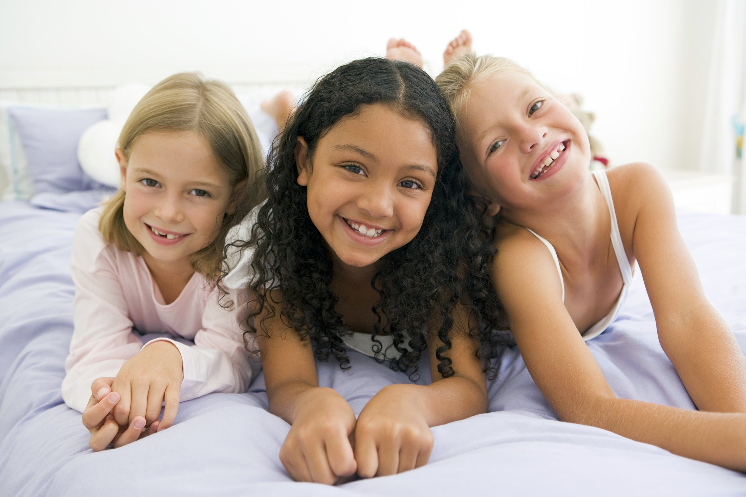 Three girls lying in bed for a slumber party