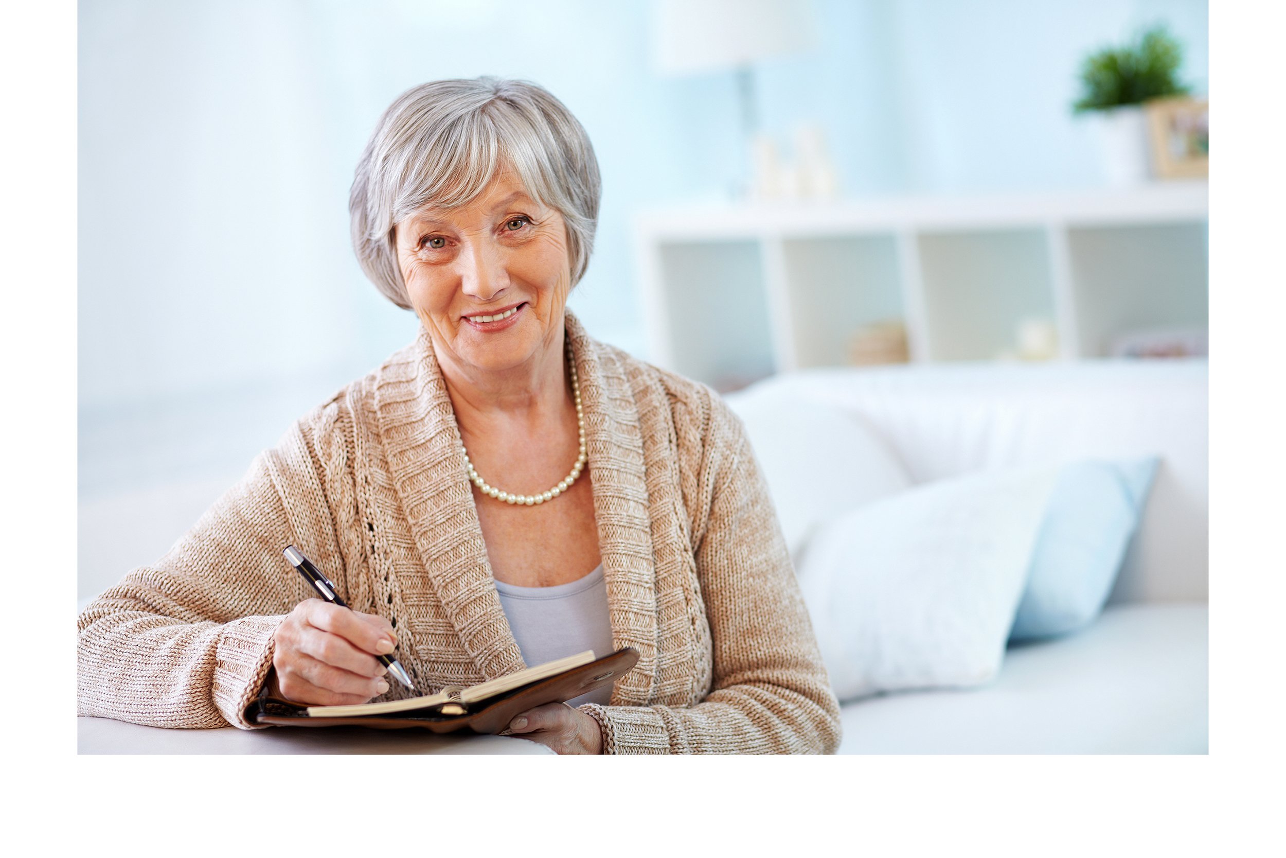 Happy senior woman at home writing in a notebook