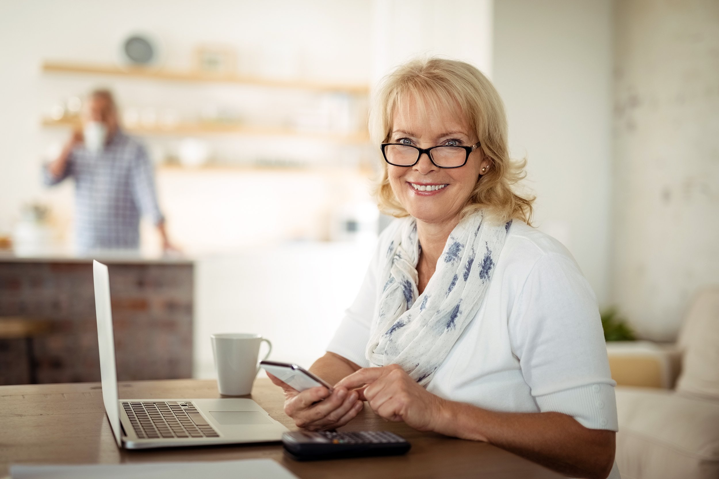 Senior woman using mobile phone and laptop at home