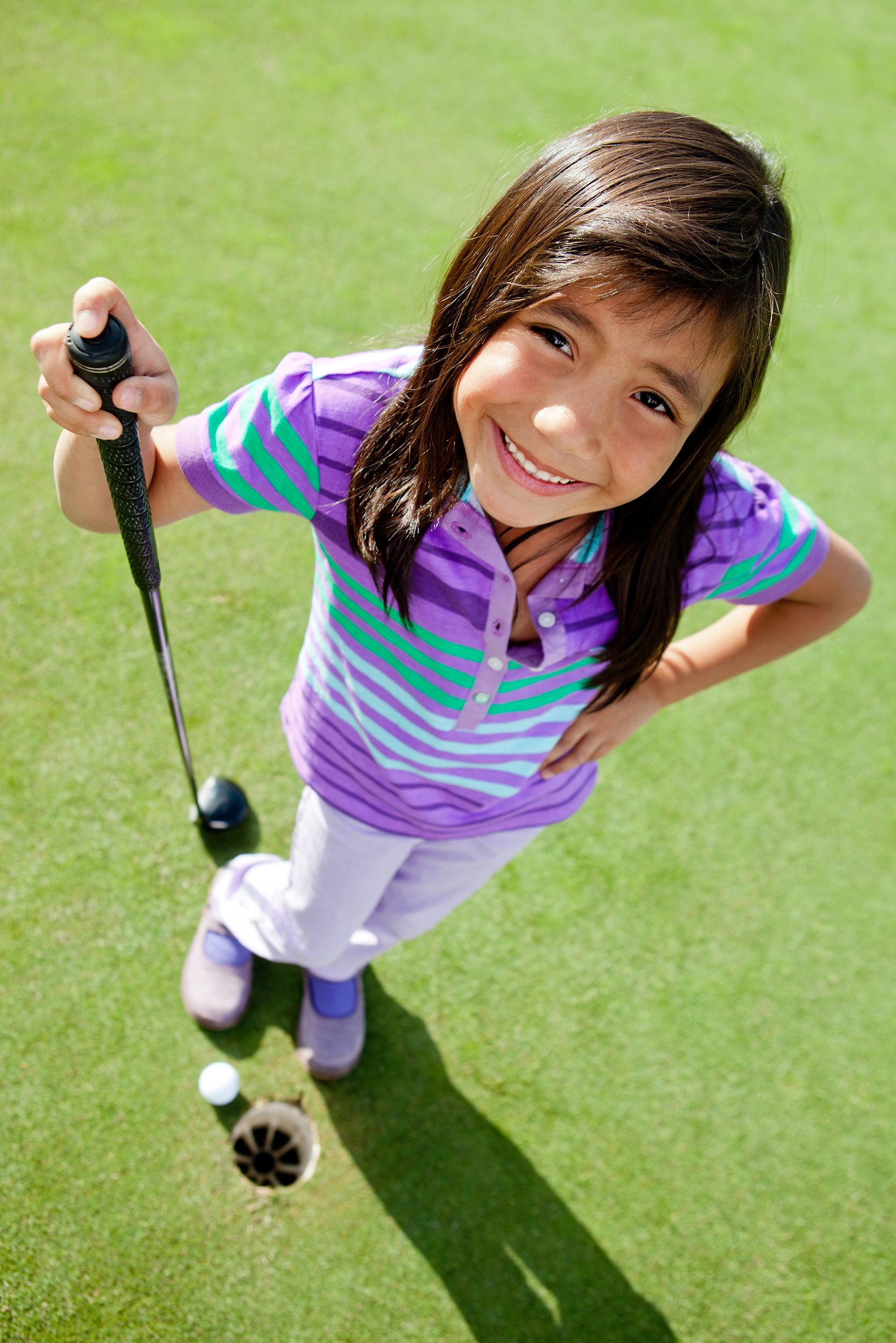 girl golf player standing next to the hole