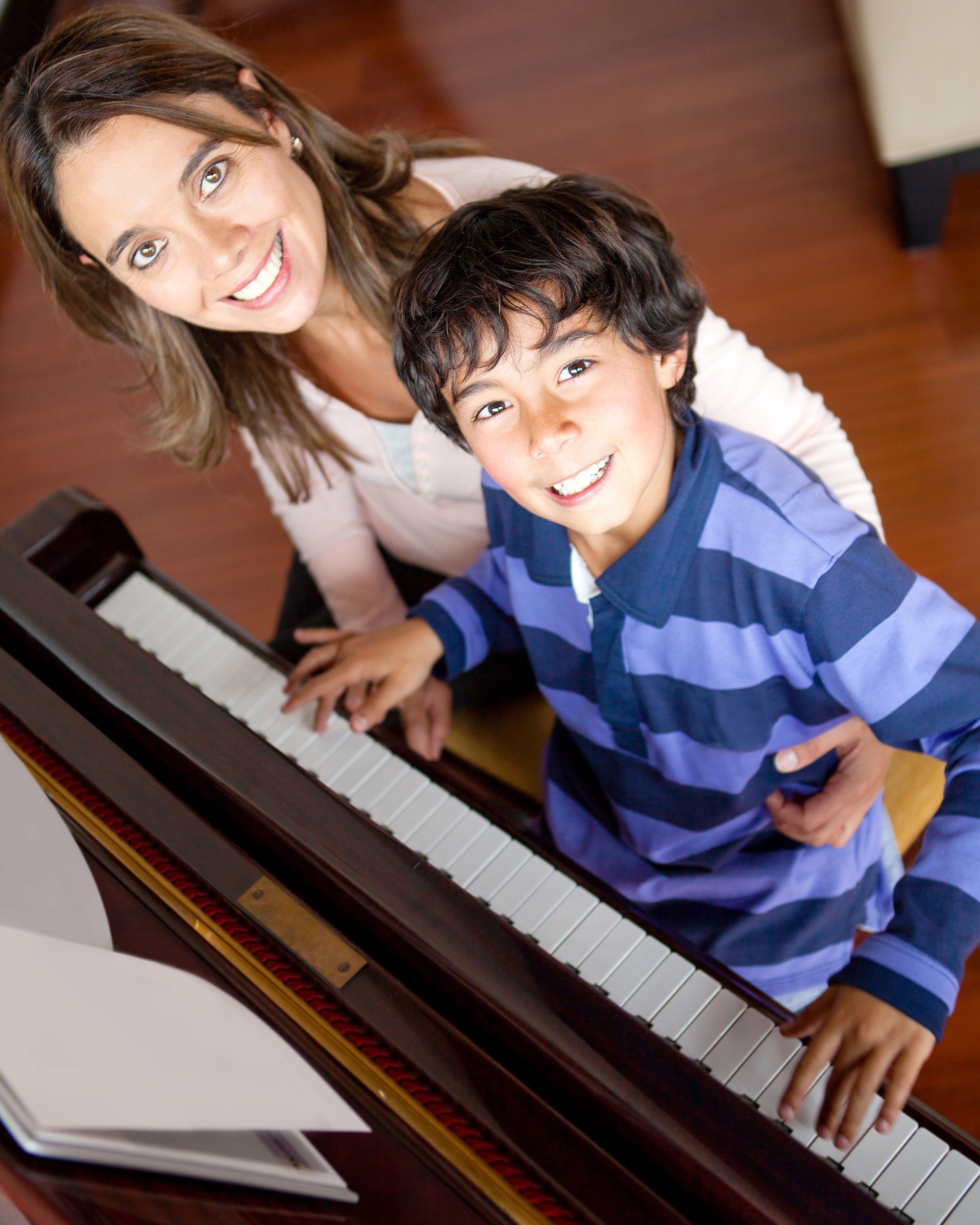 boy learning how to the play piano with teacher