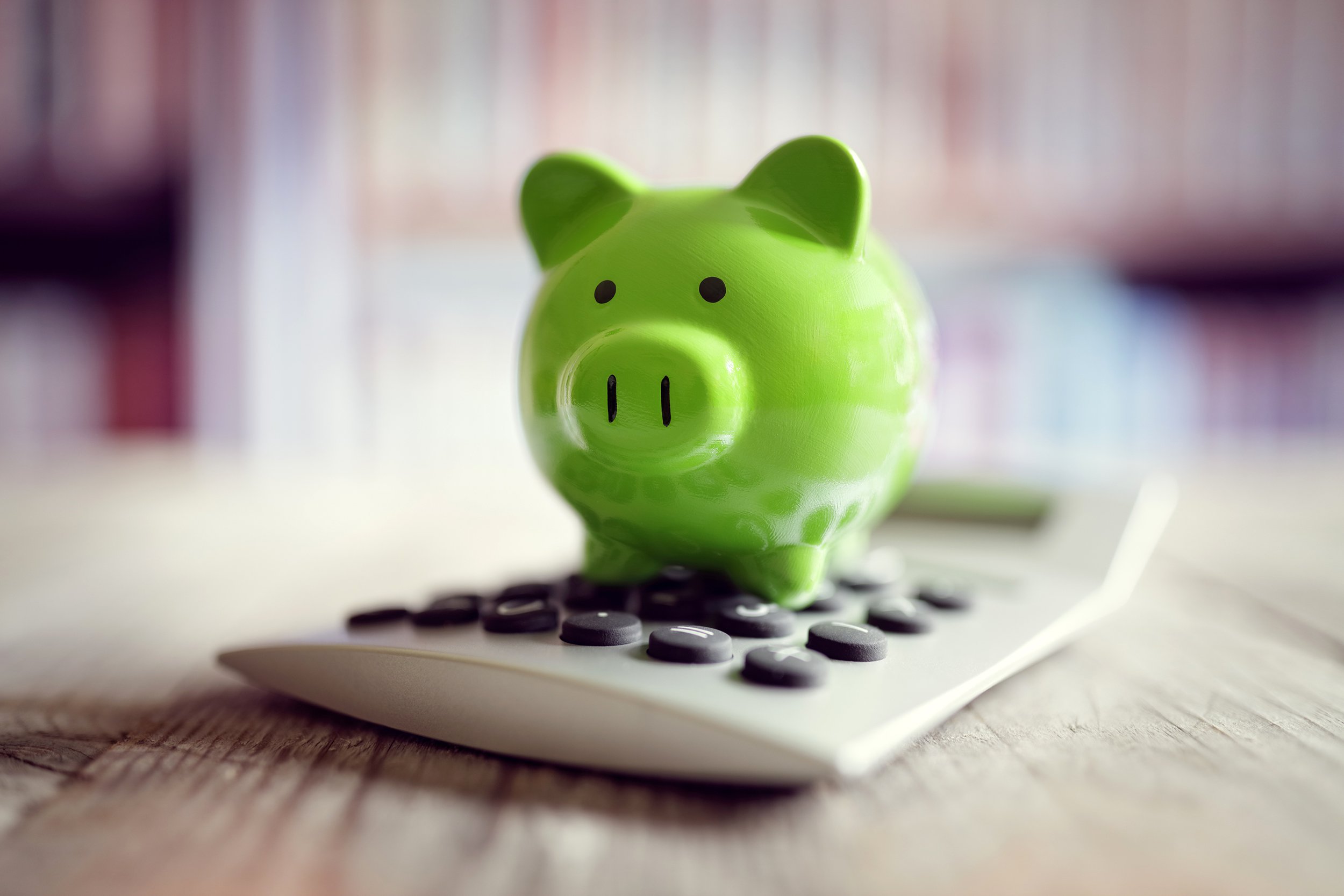 Green piggy bank on top of calculator