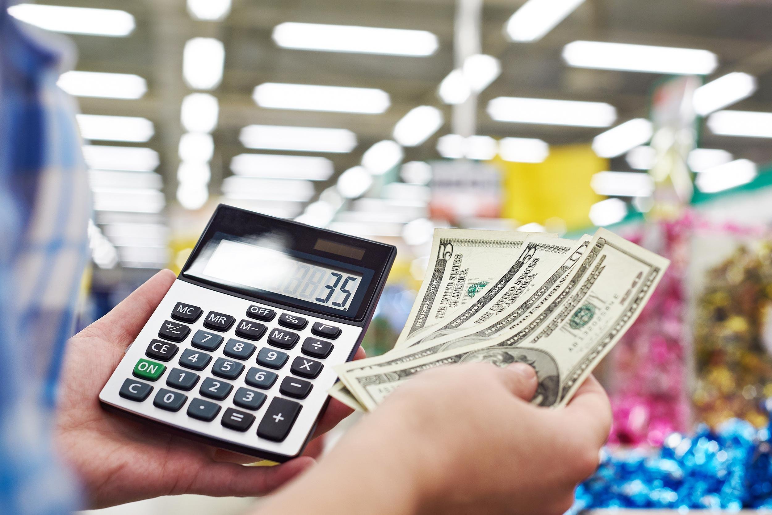 hands holding bills and calculator at dollar store
