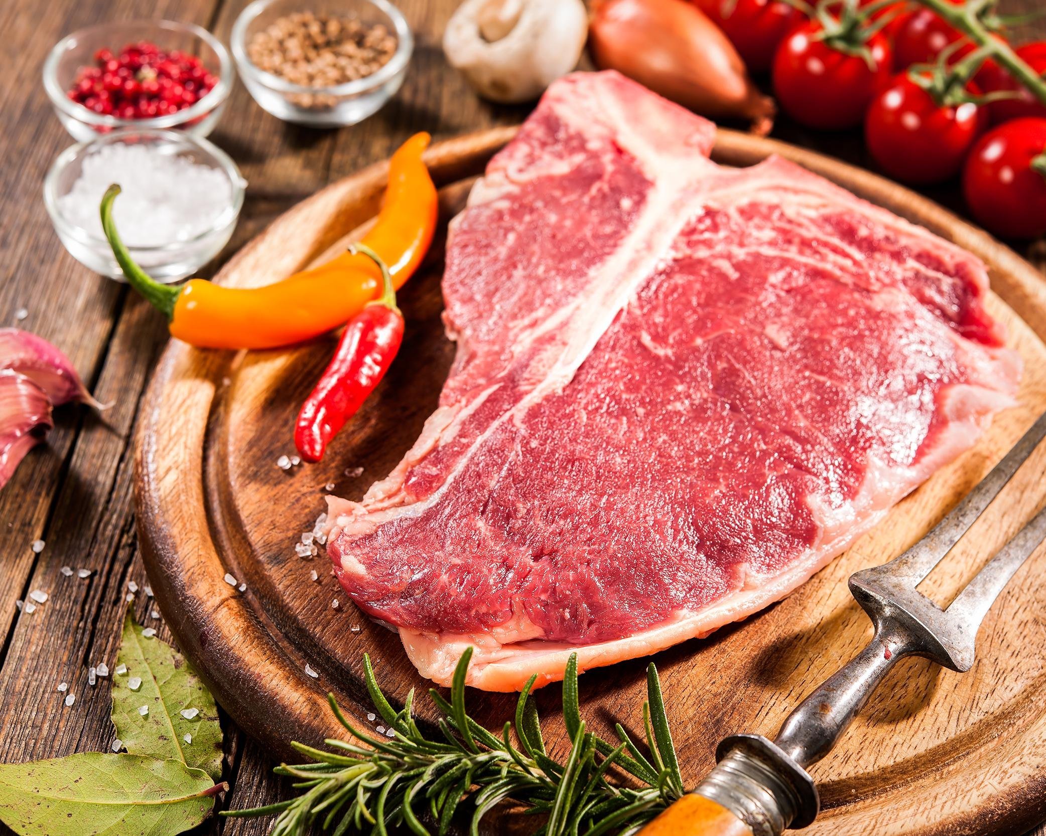 raw fresh meat t-bone steak and seasoning on wooden background