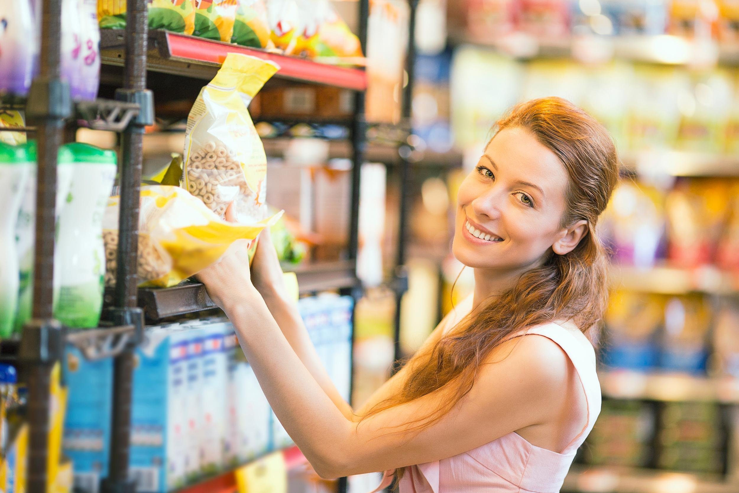 smiling woman shopping for bulk cereal in grocery supermarket