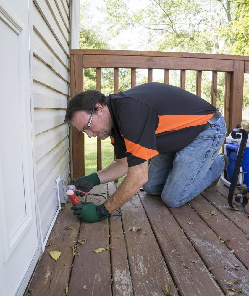 man is checking external electrical outlet on his deck with a voltage meter