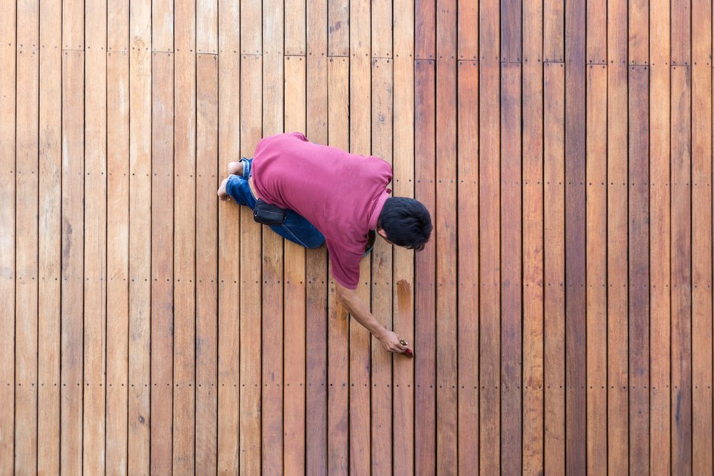 man is staining a deck near a pool