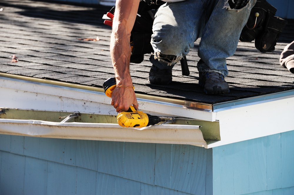 man repairing gutters on roof