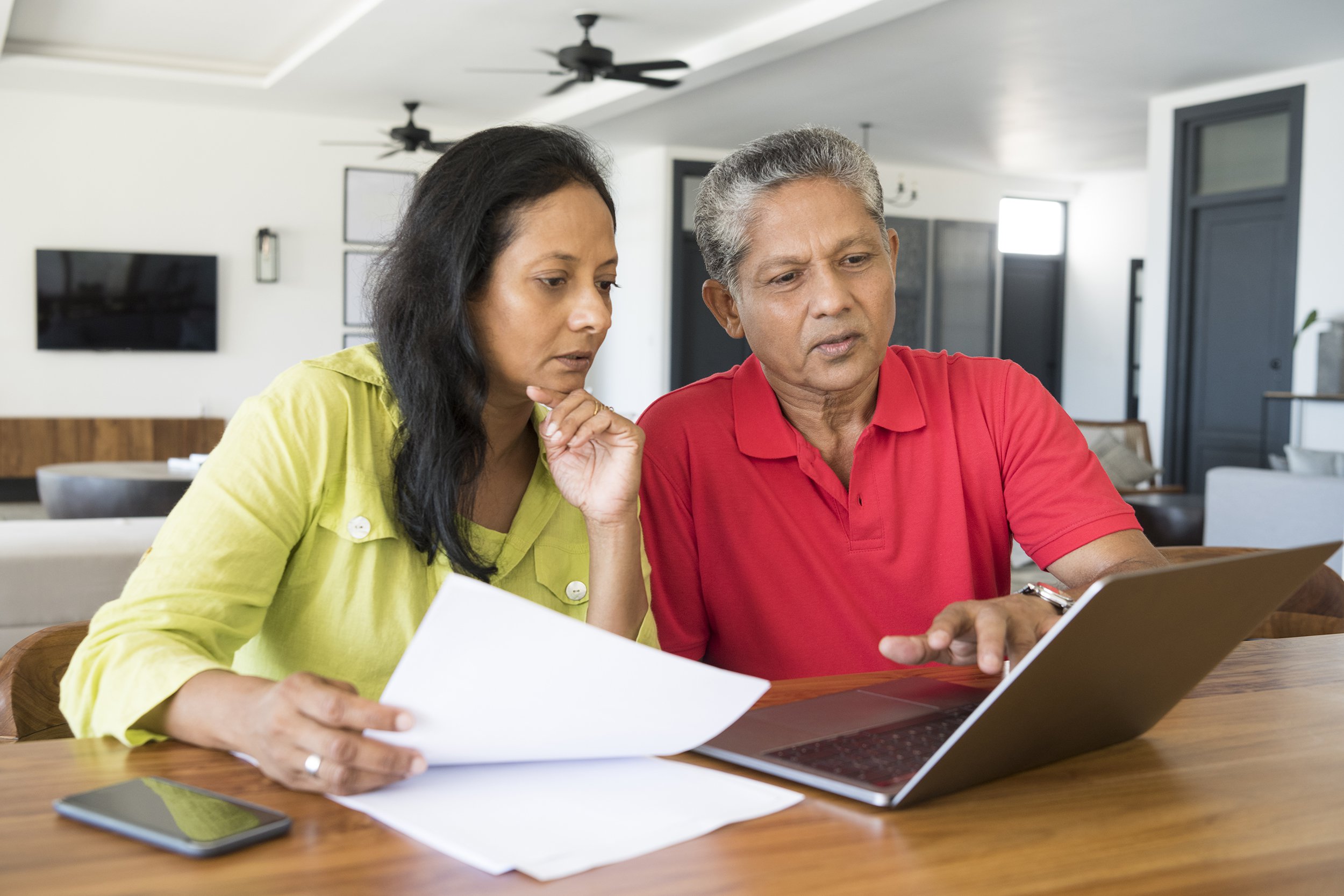 Sri Lankan couple using laptop at home with paperwork