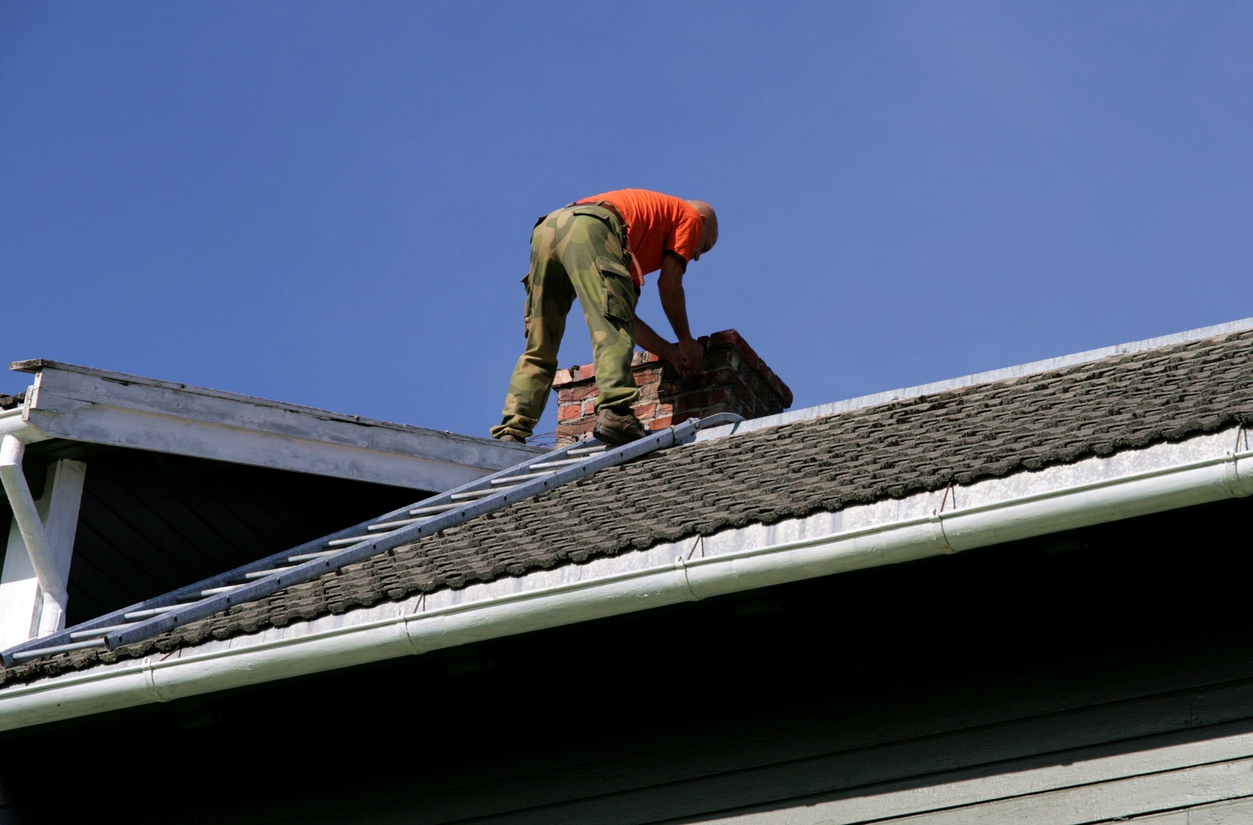 man on the roof of his house inspecting his chimney